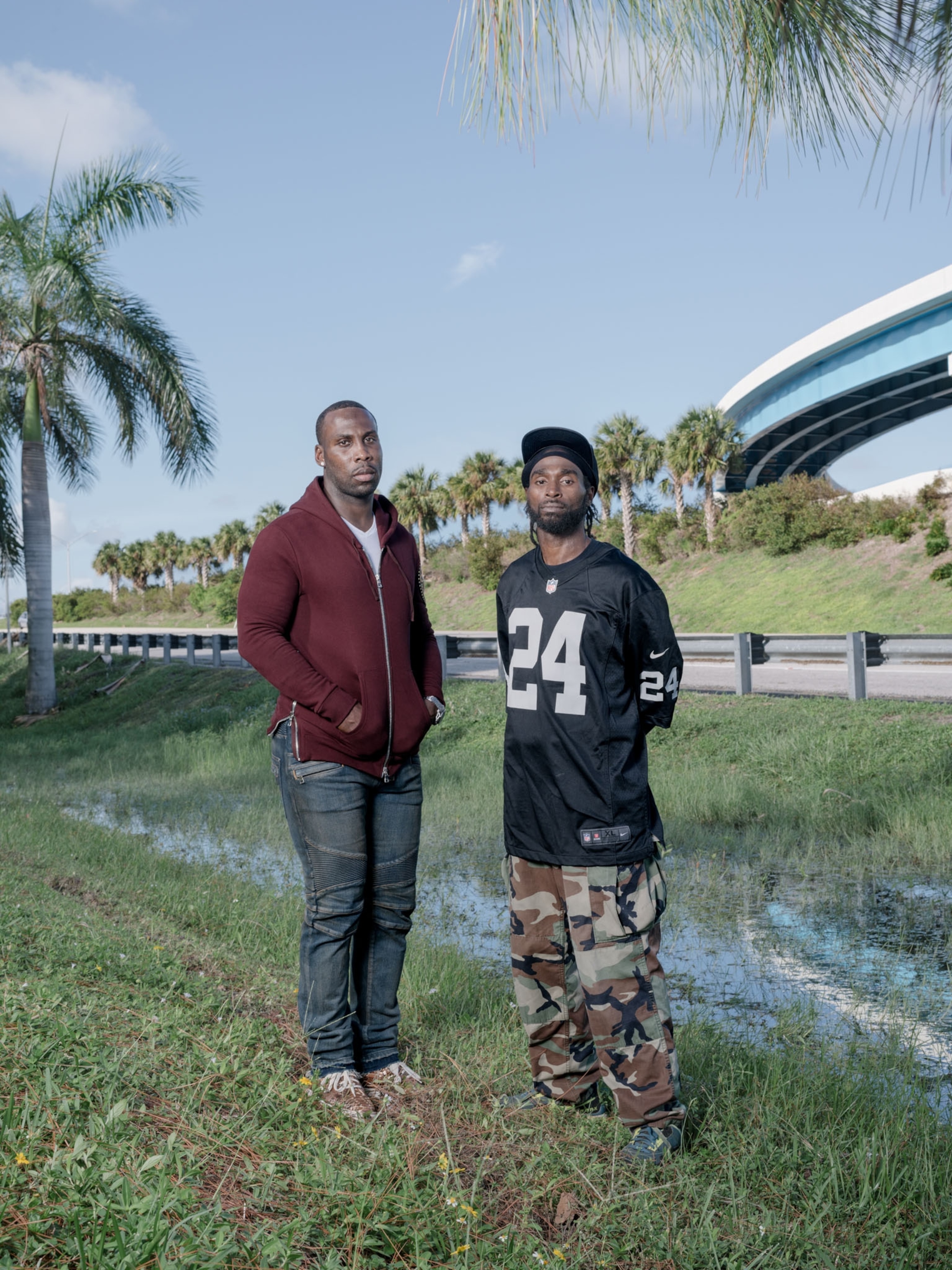 2 young African American men standing for a portrait in a tropical setting by a highway