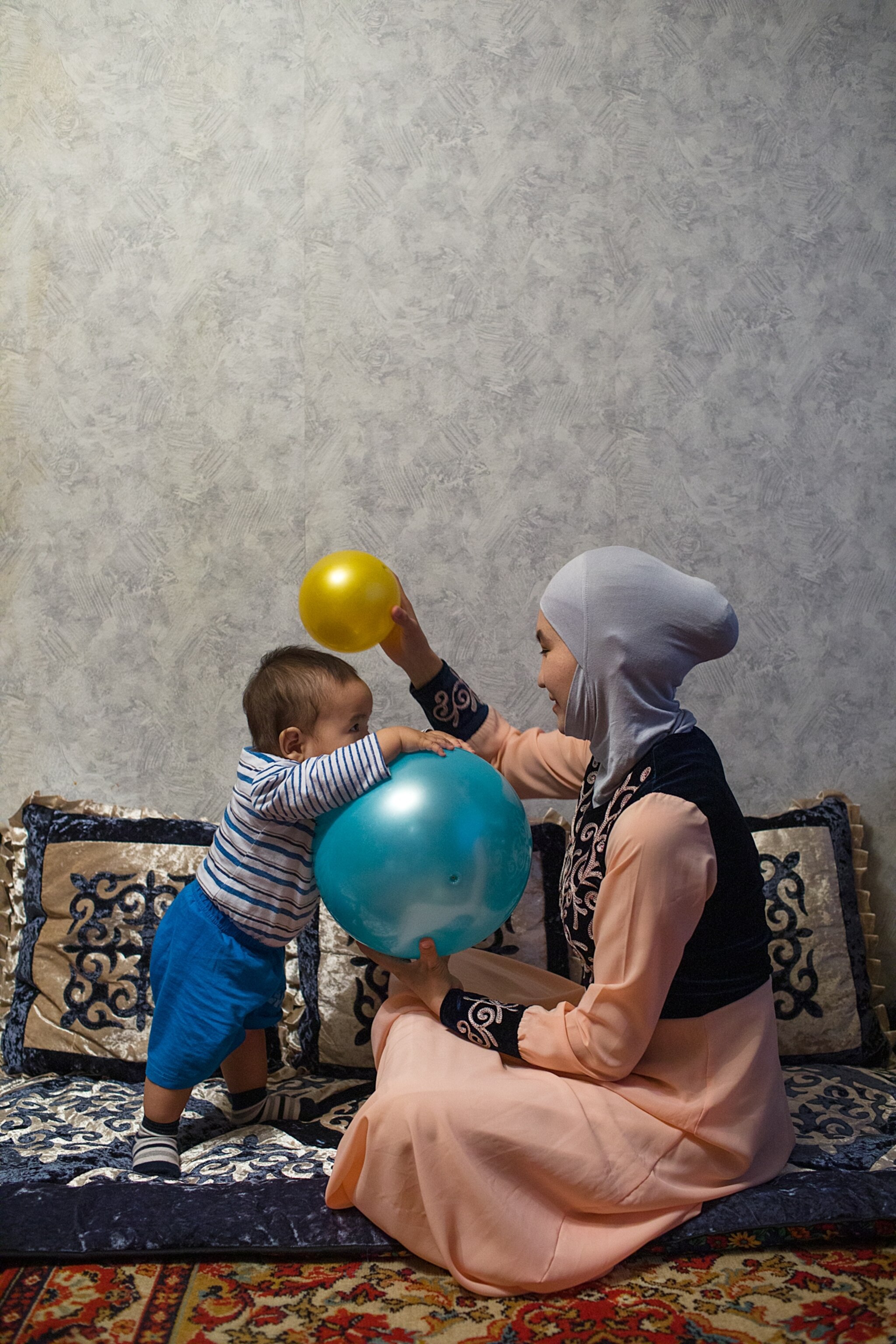 a woman playing with a child and two balloons