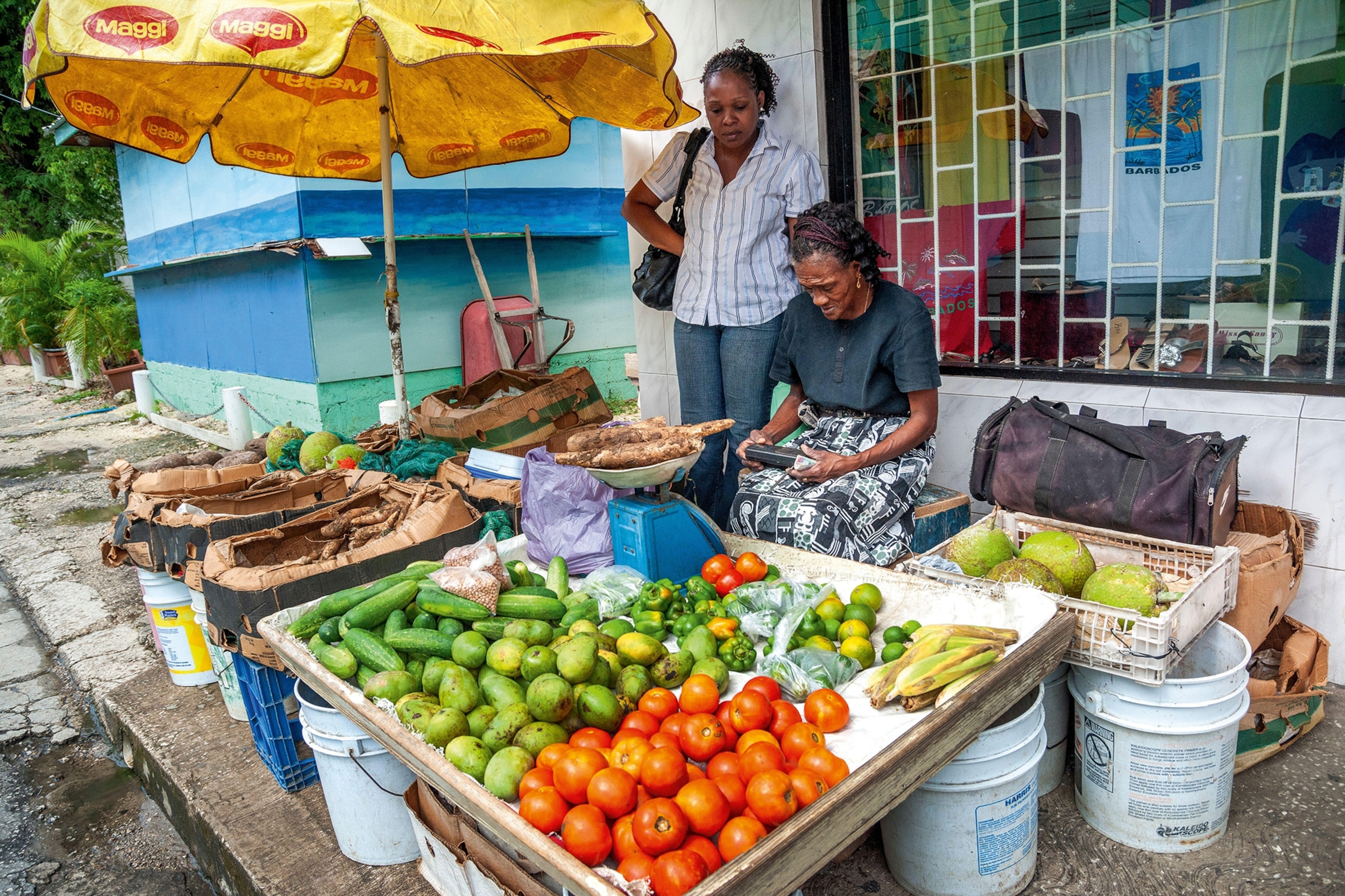 Vendors behind a fruit and veg stall at a local Bajan market.