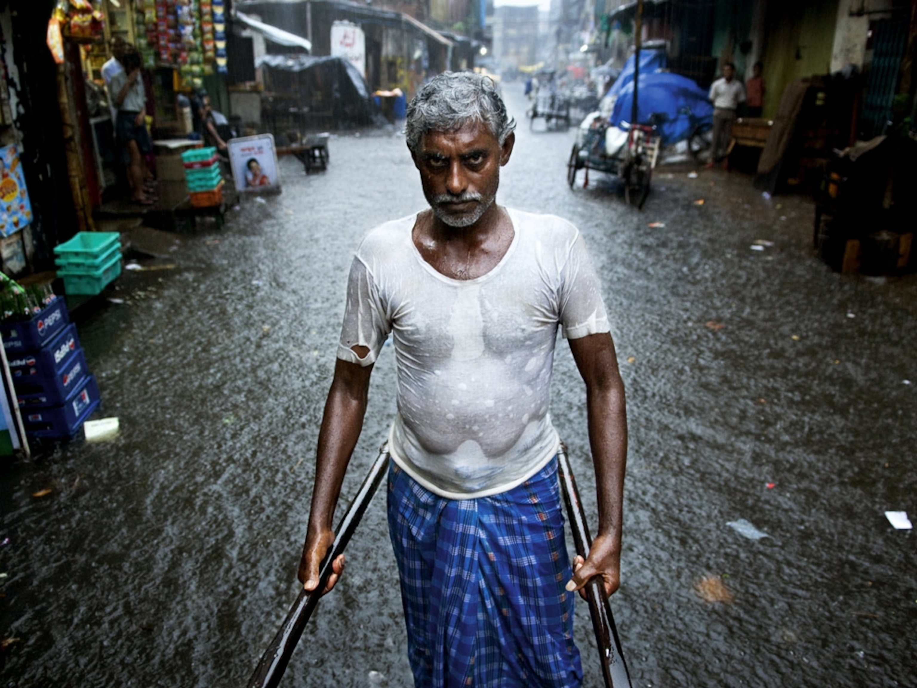 a ricksha driver in a flooded street in Kolkata, India