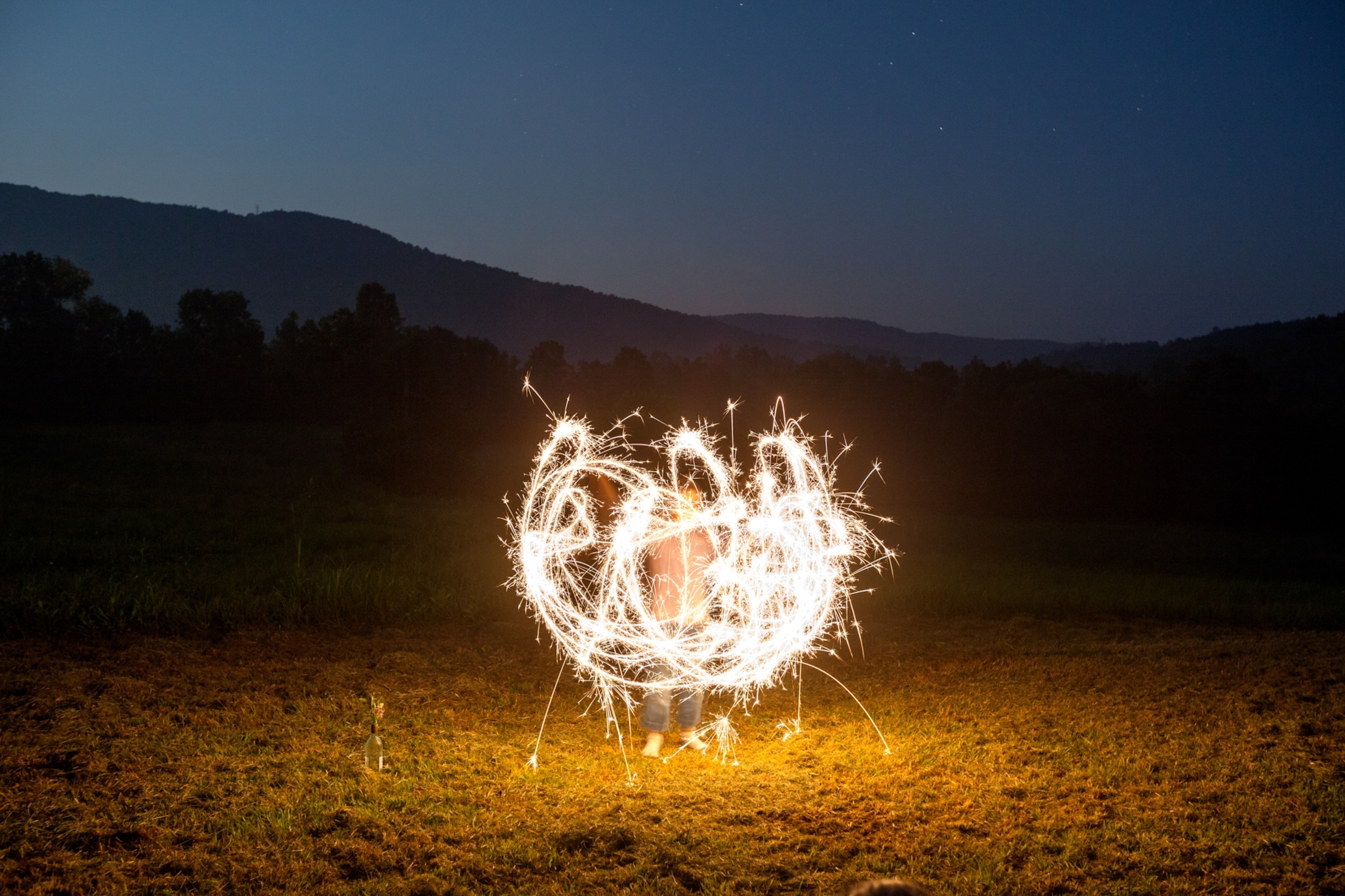 A child plays with sparklers in a field