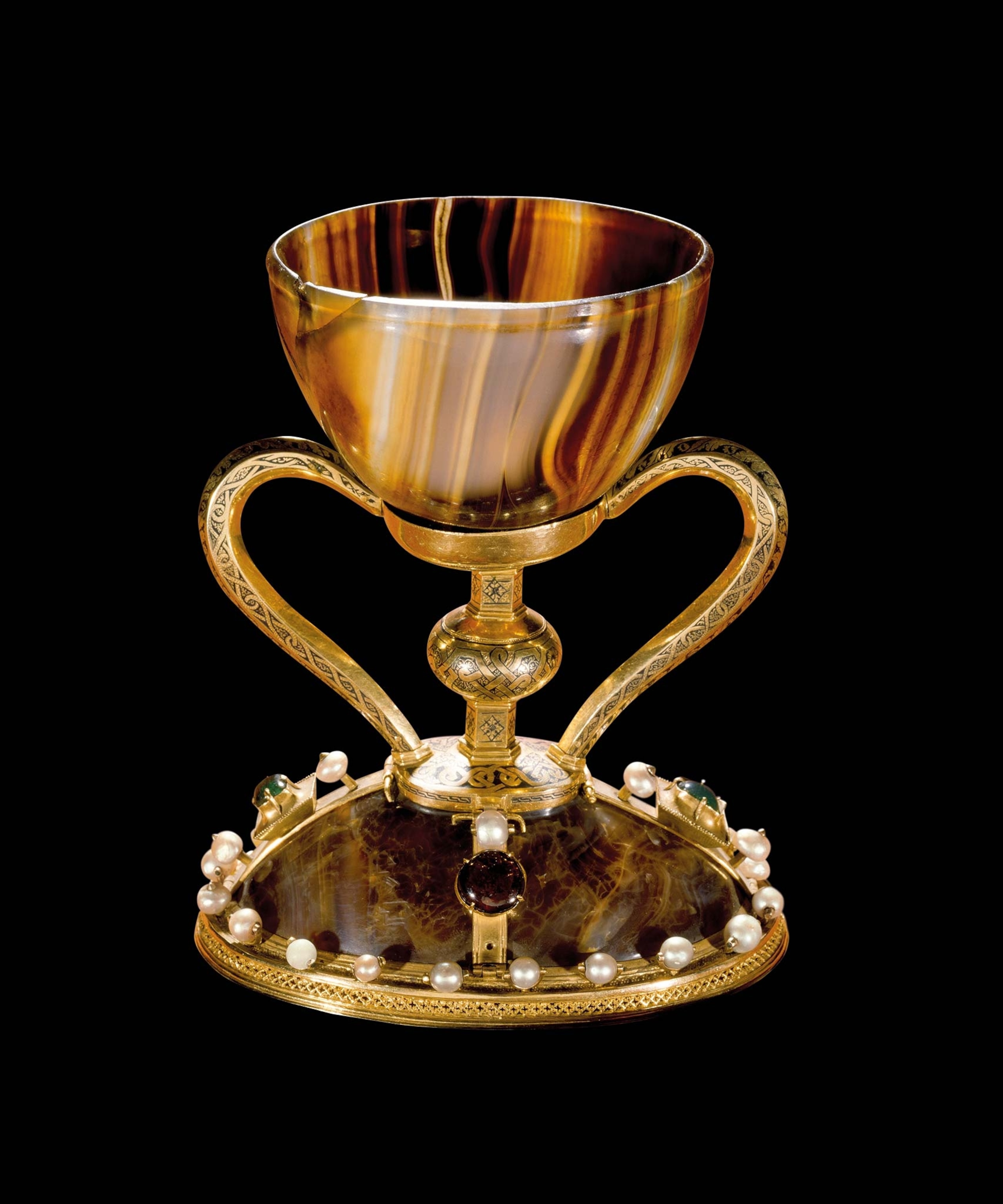 An ornate golden chalice with stones on the bottom