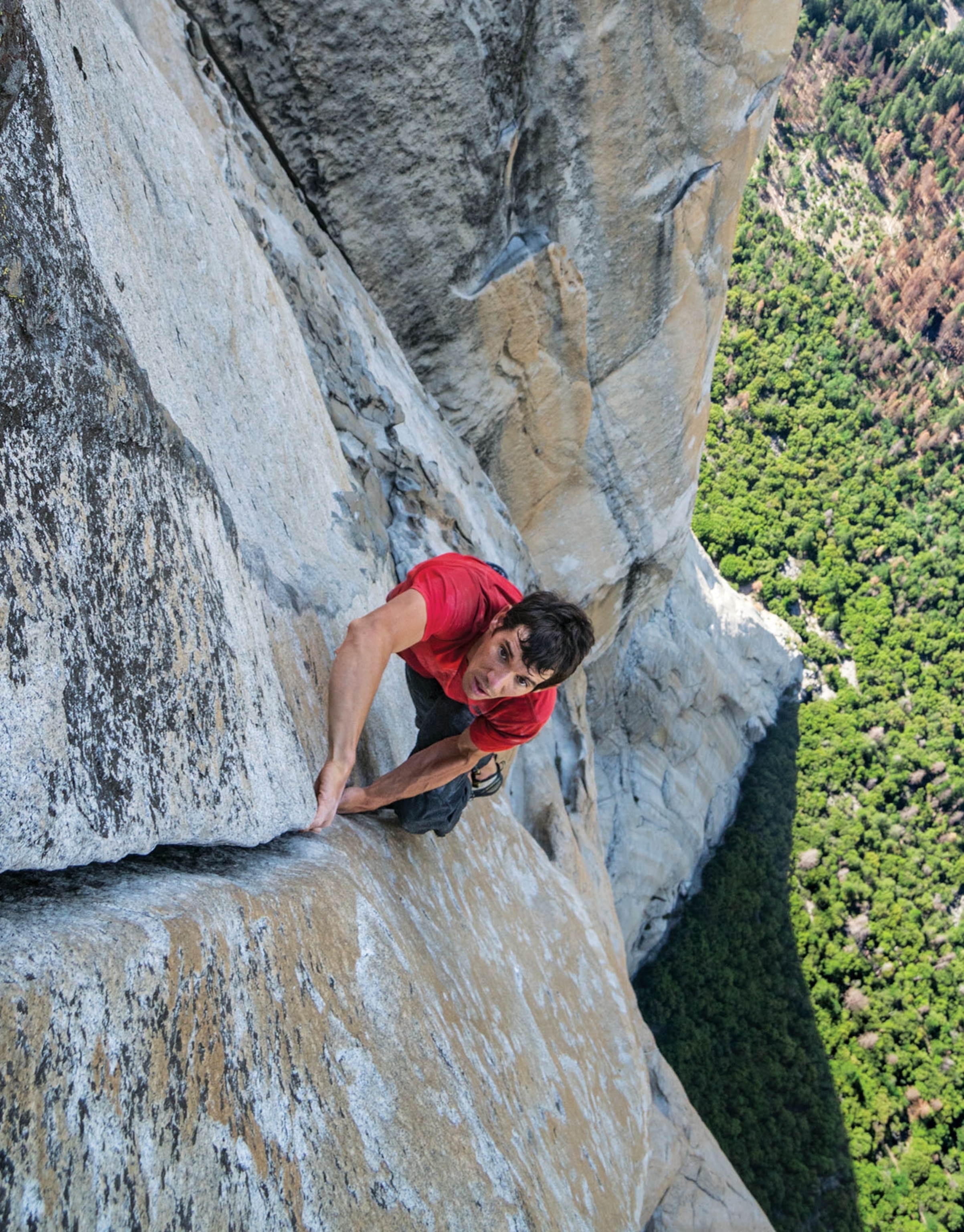a man climbing a rocky mountain facade without assistance