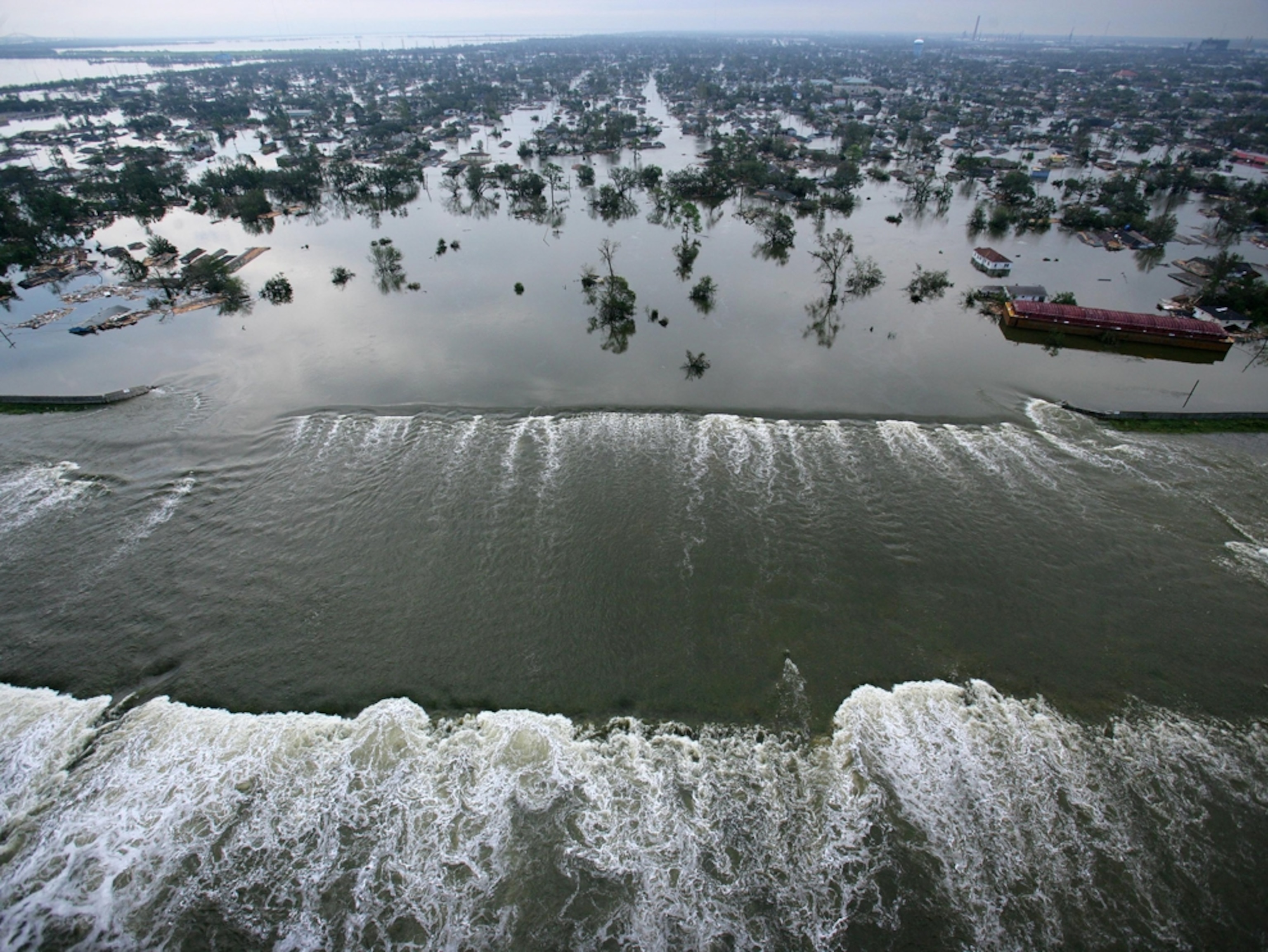 Aerial view of water flowing past a broken levee