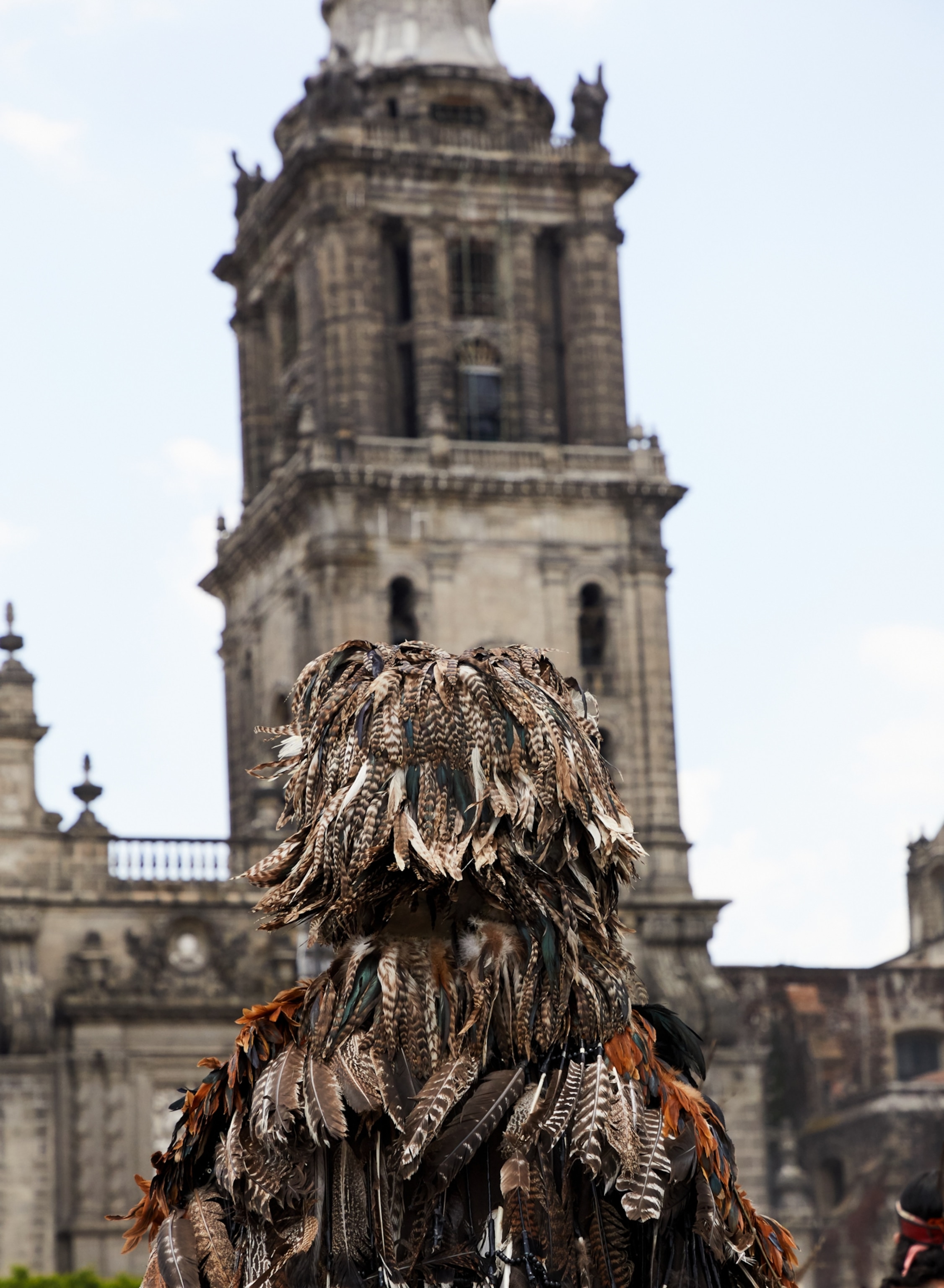 a dancer dressed with feathers dances outside of the cathedral in Mexico City