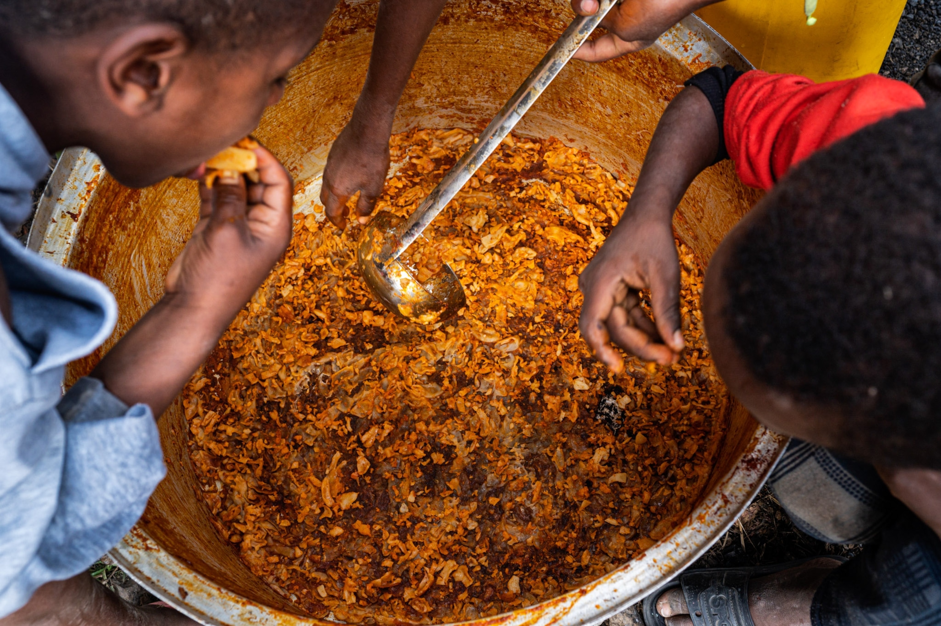children eating food out of a pot