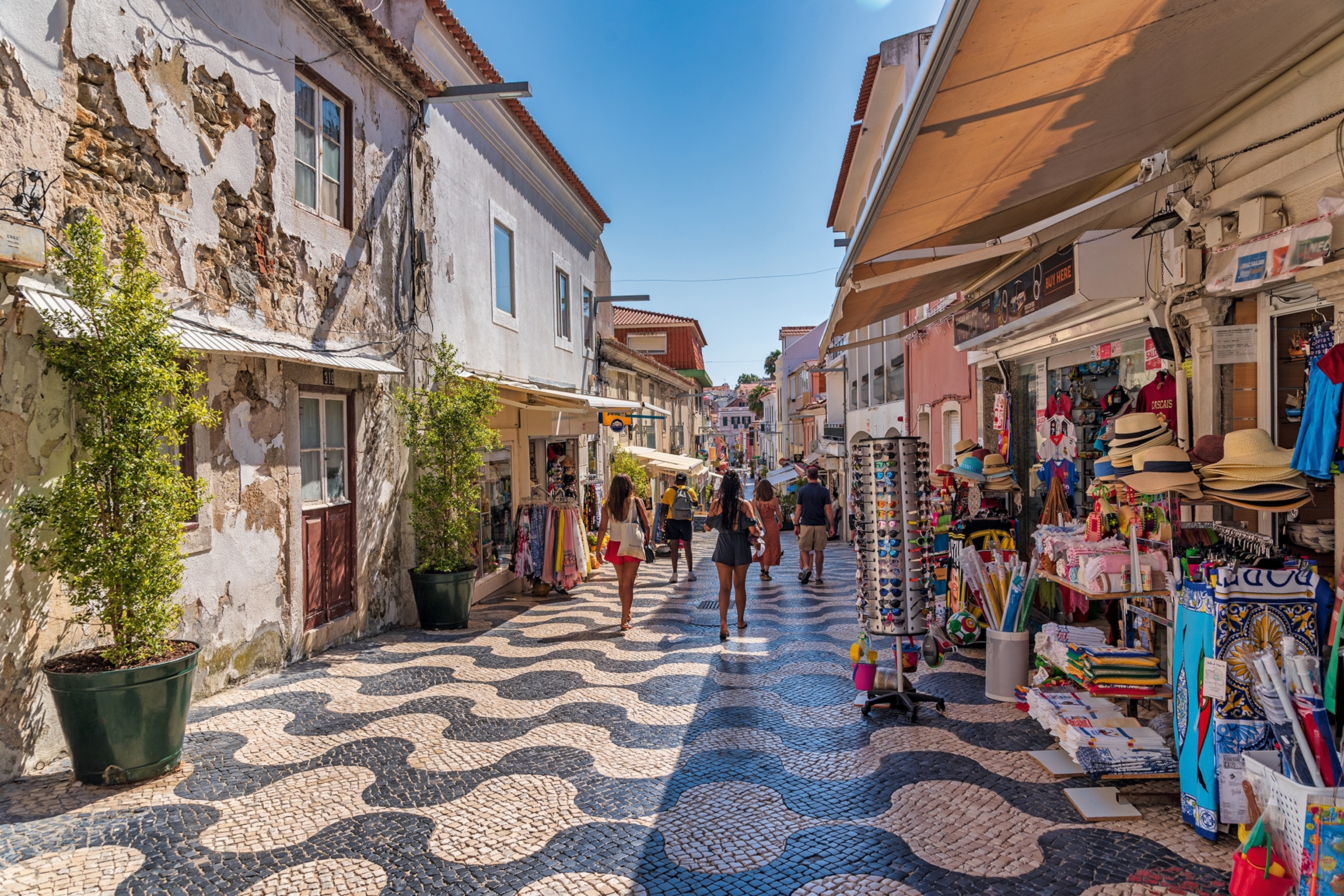 People walking down a tiled shopping street in the sun