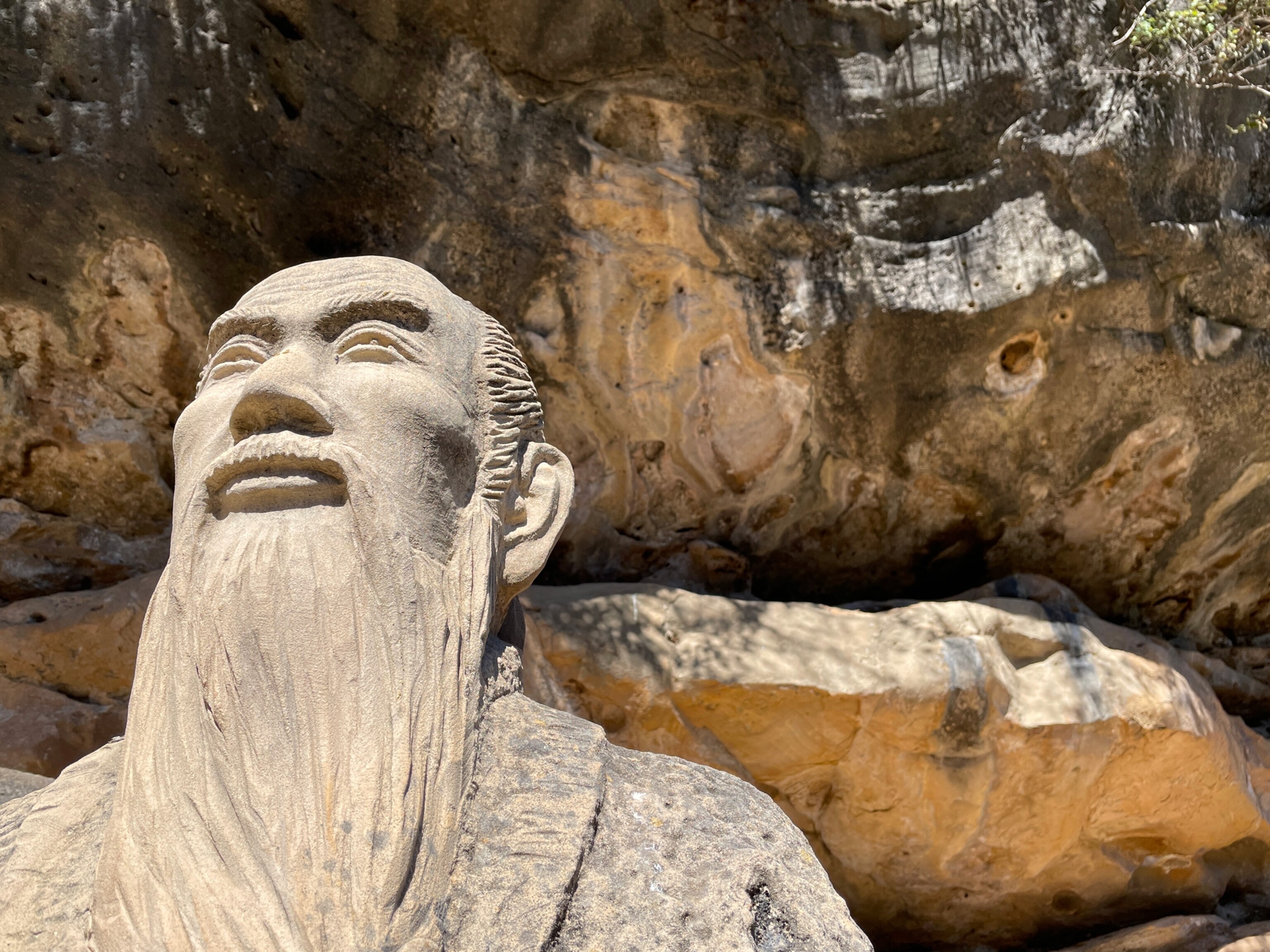 Picture of statue of man with long beard with rocks in background