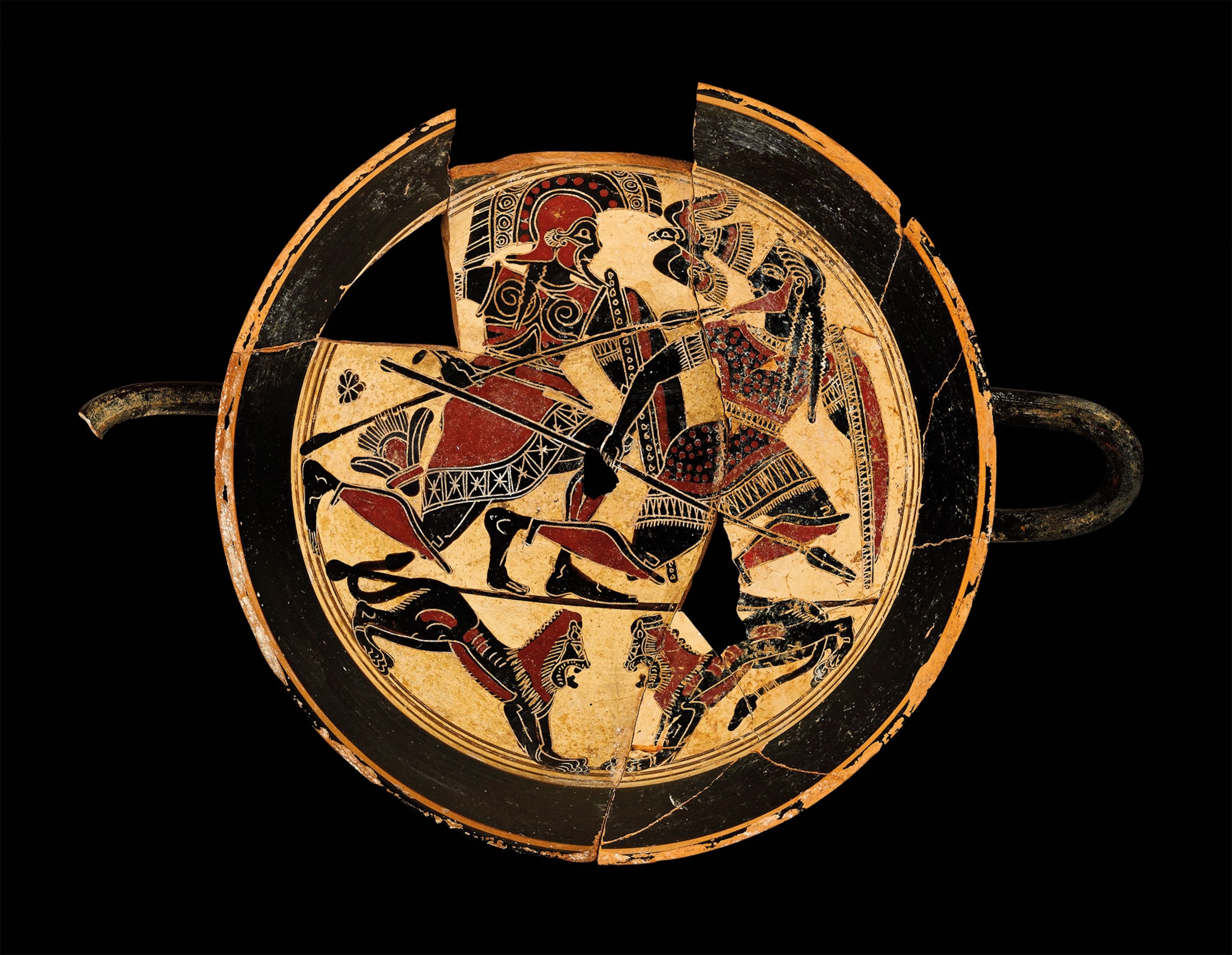 A circular vase with black, white, and red shows 2 Spartan soldiers bearing hoplite panoply