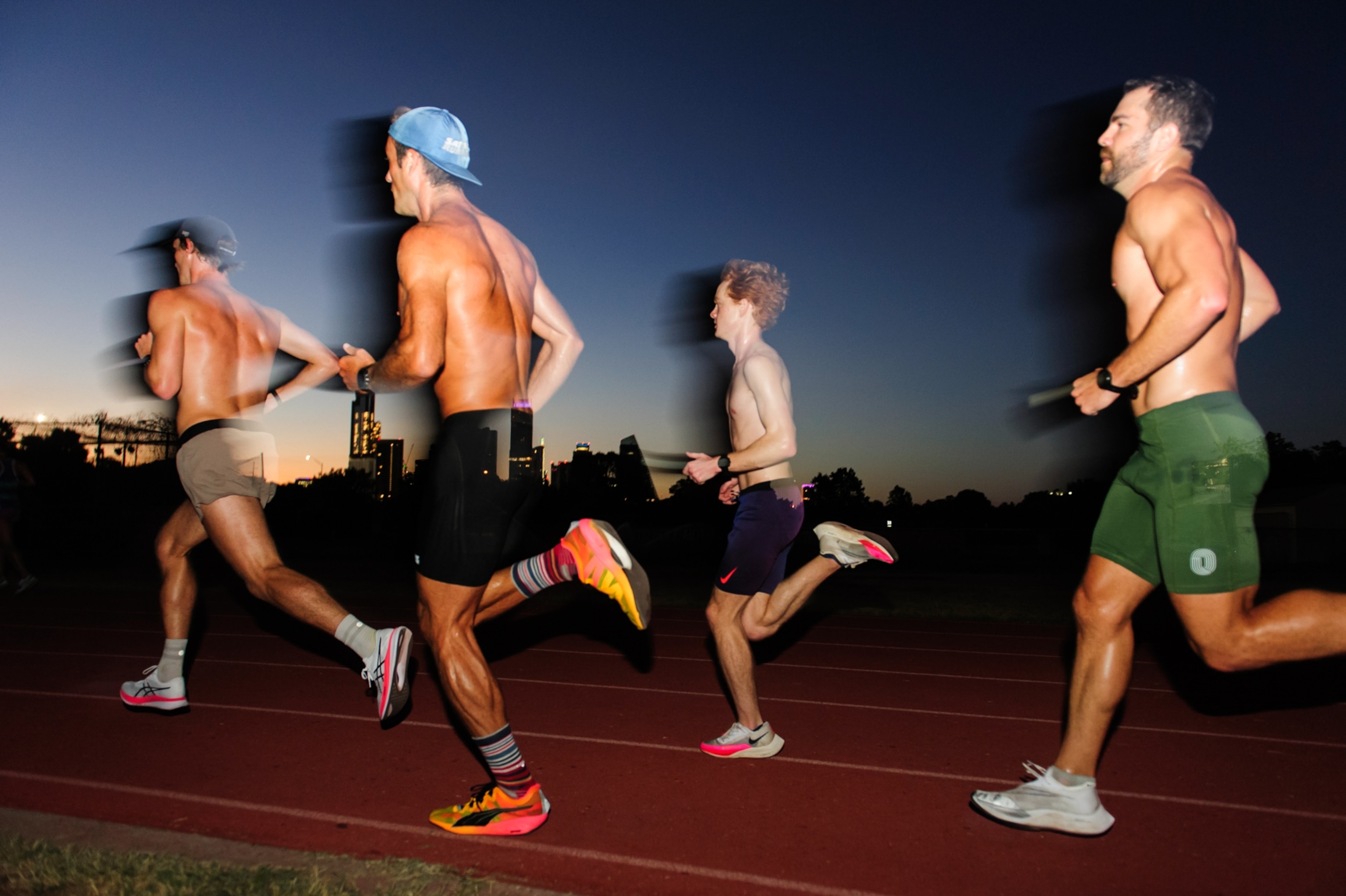 Four men running on a track, dawn light visible on the horizon.