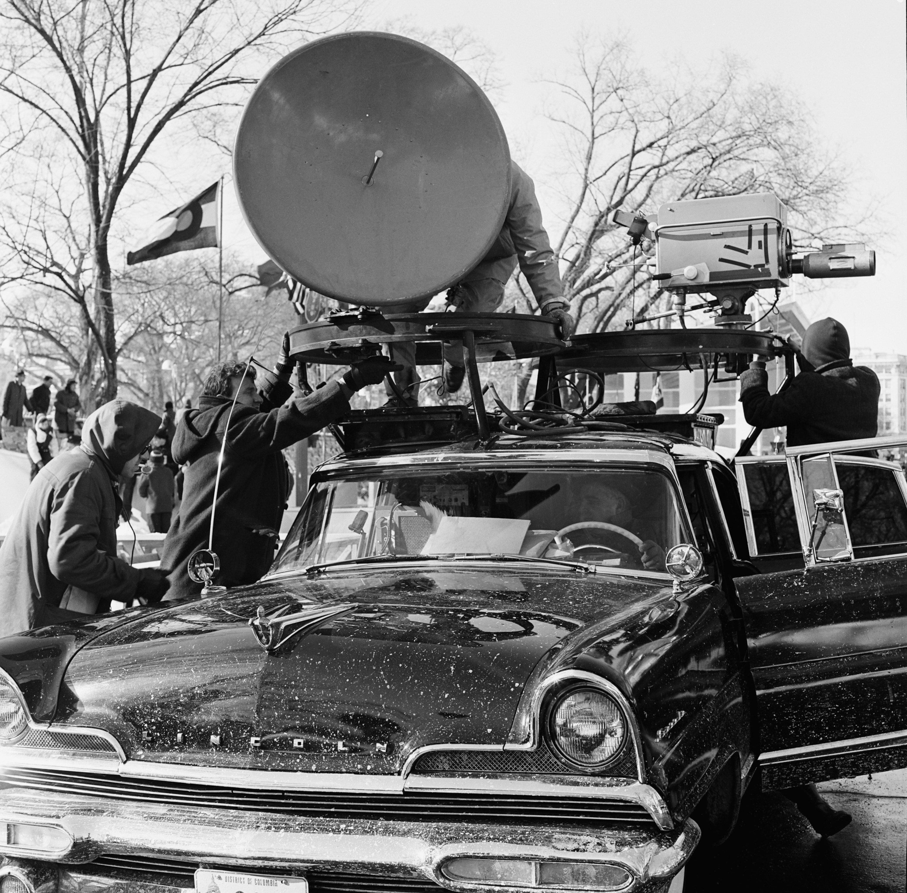 a car with a satellite on top being operated by a news crew
