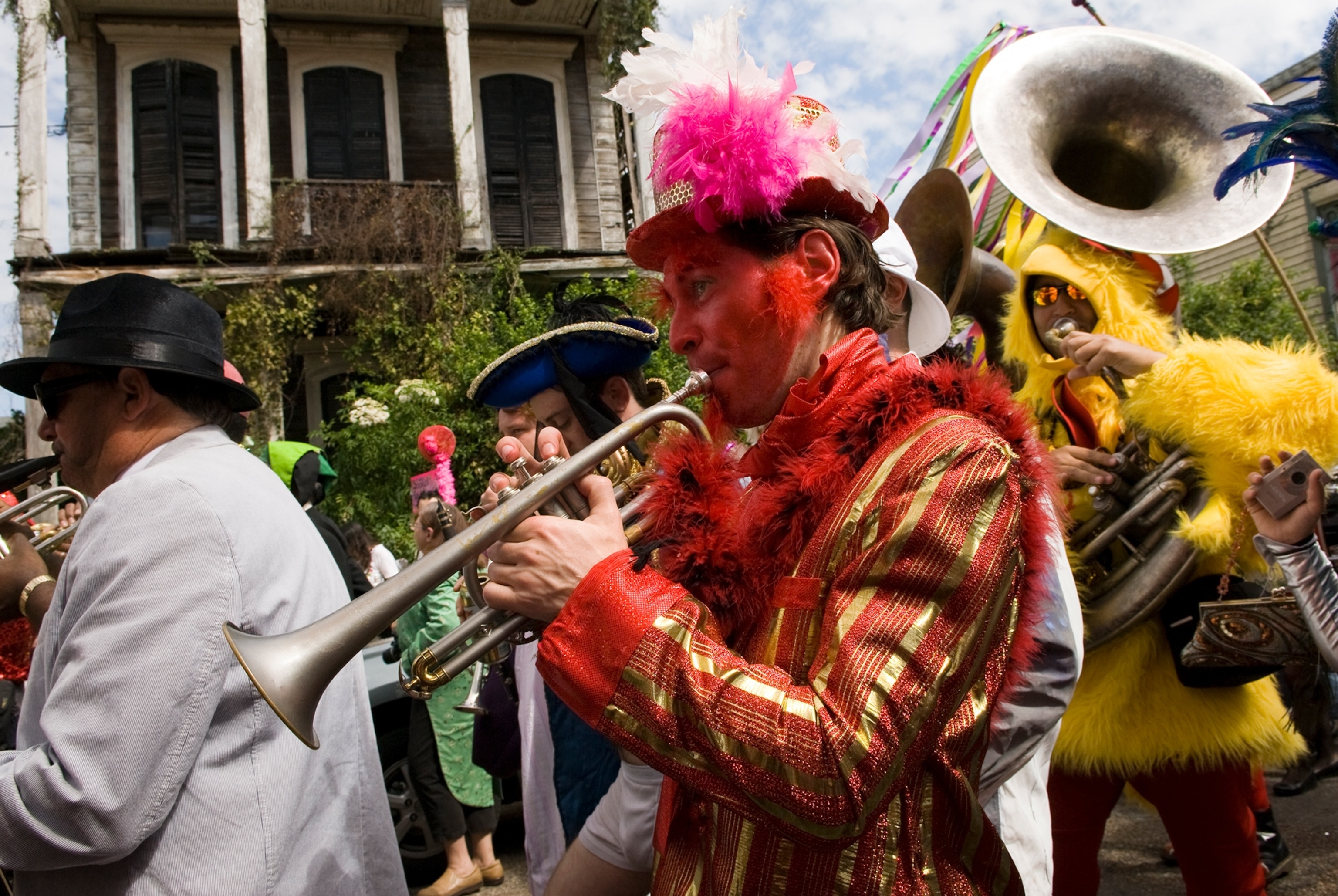A man dressed as a devil plays trumpet in the St. Anne parade.