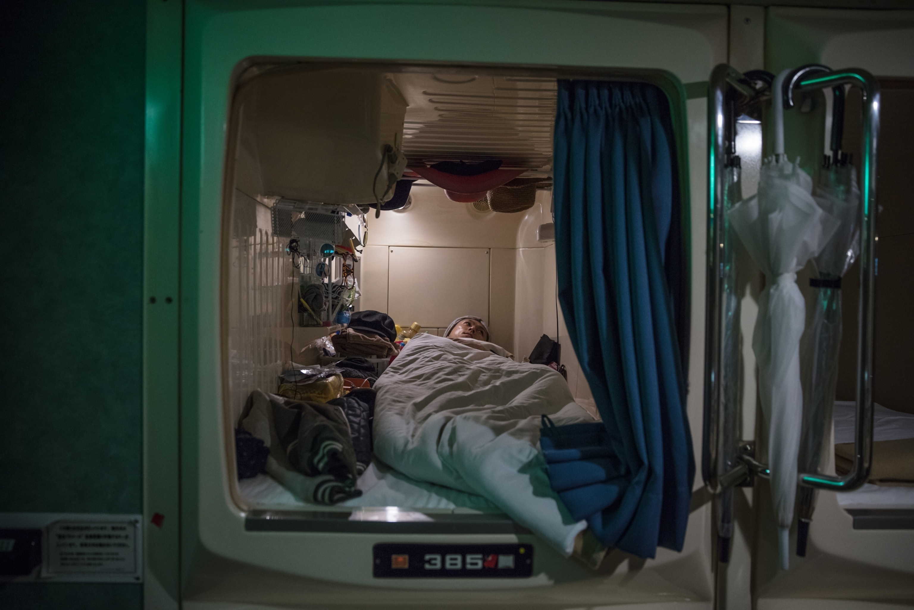 a man sleeping in his capsule hotel bedroom