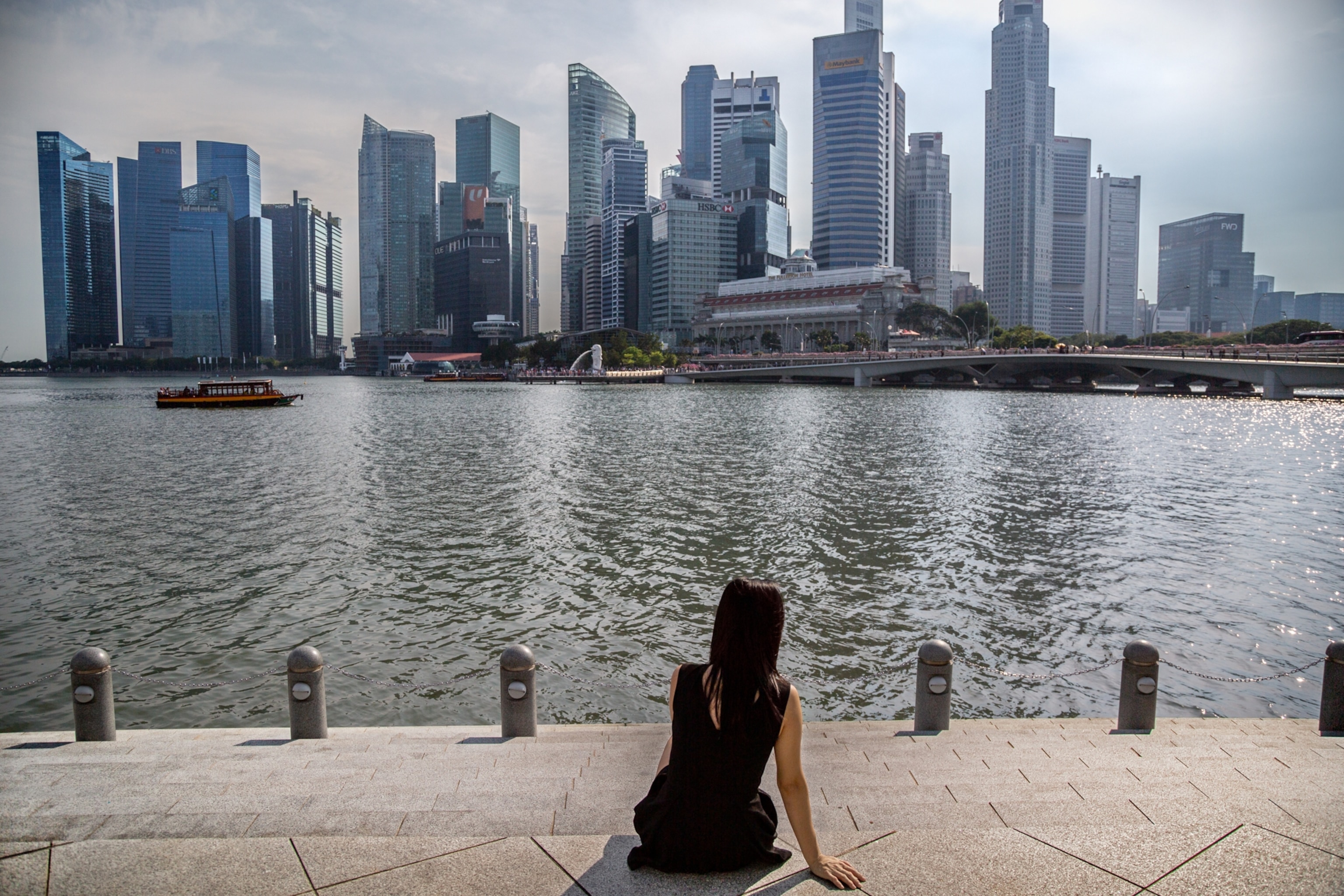 woman on the steps alongside a river looking at a city