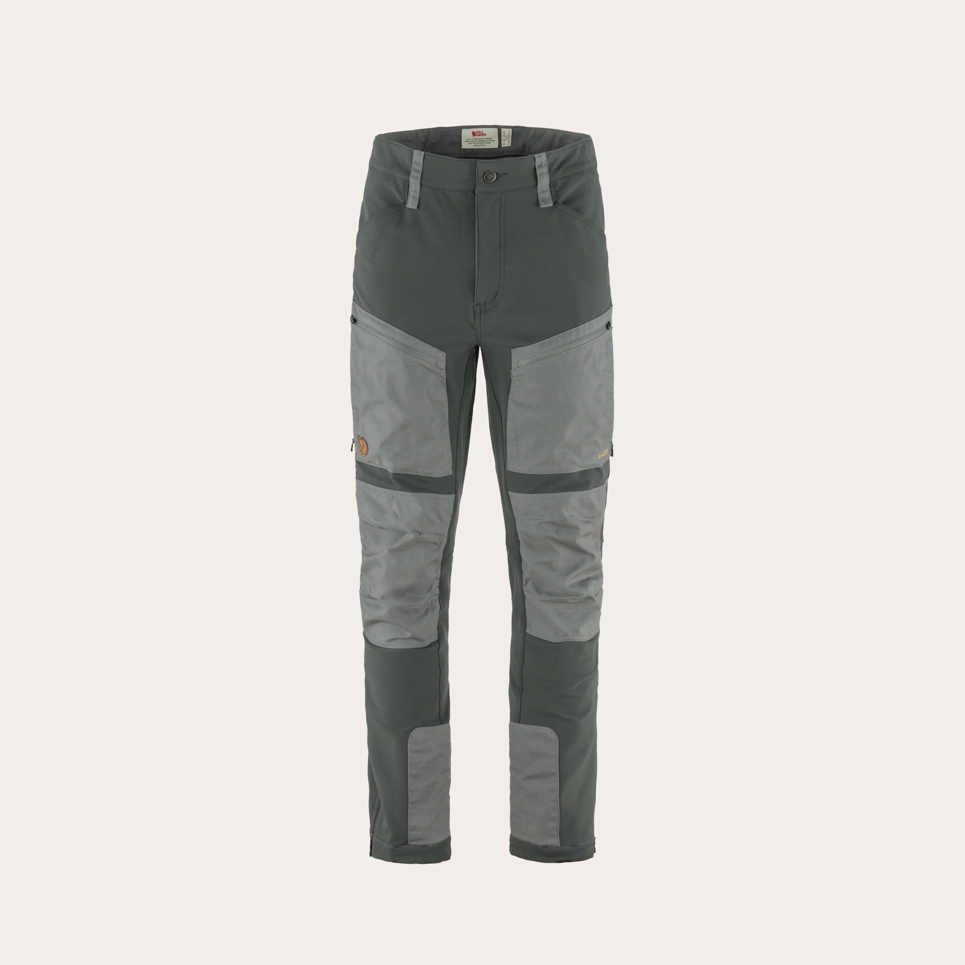 Dark grey pants with light grey patches placed on a tan background.
