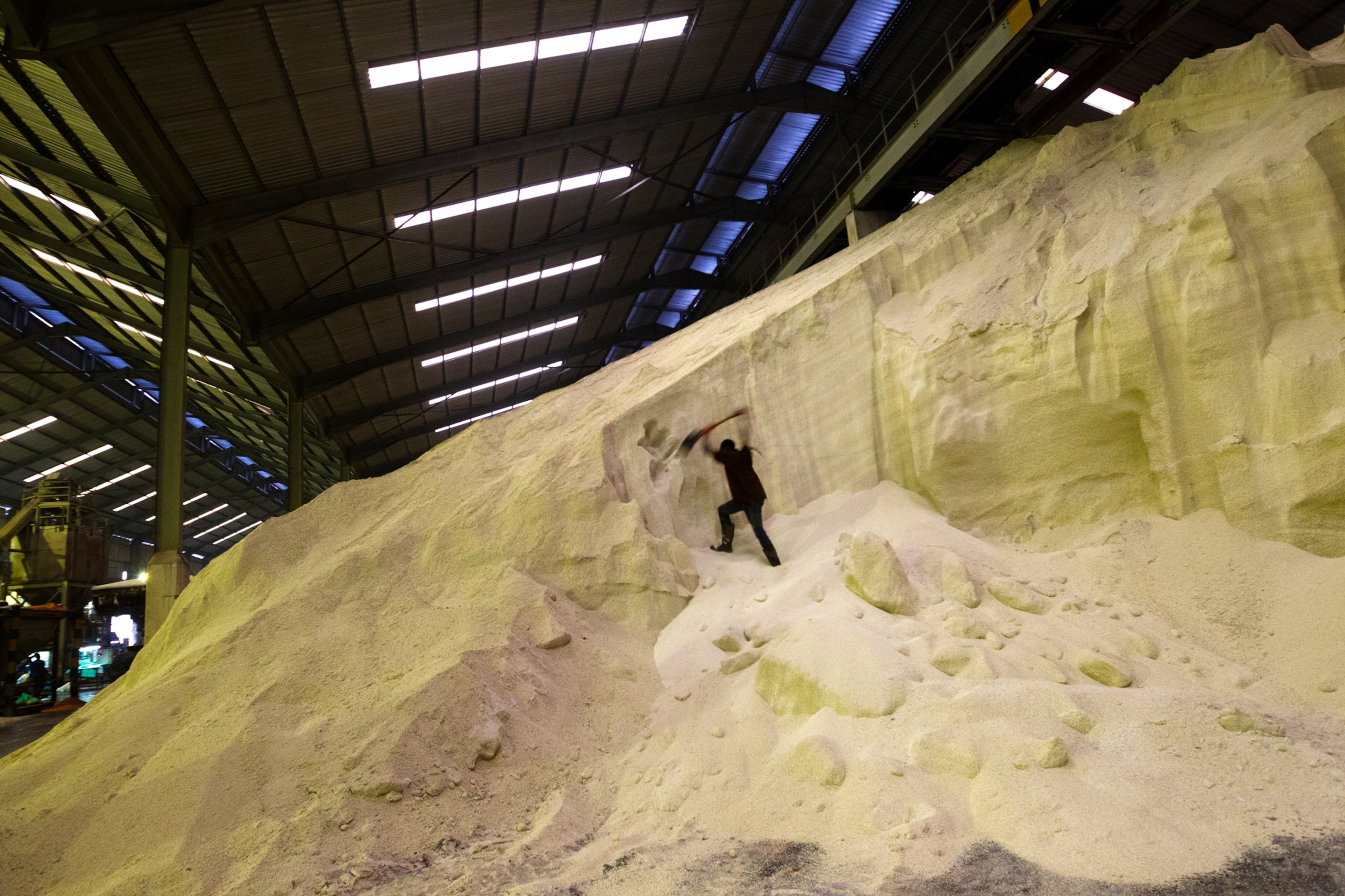 a person shovels a large pile of fertilizer in a factory