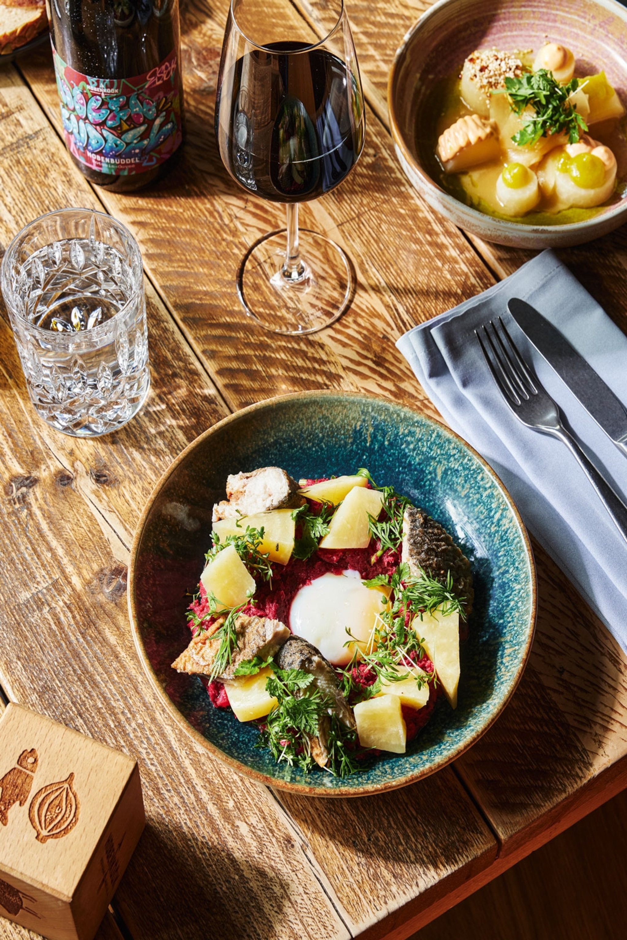 A dish of food placed alongside a glass of wine.
