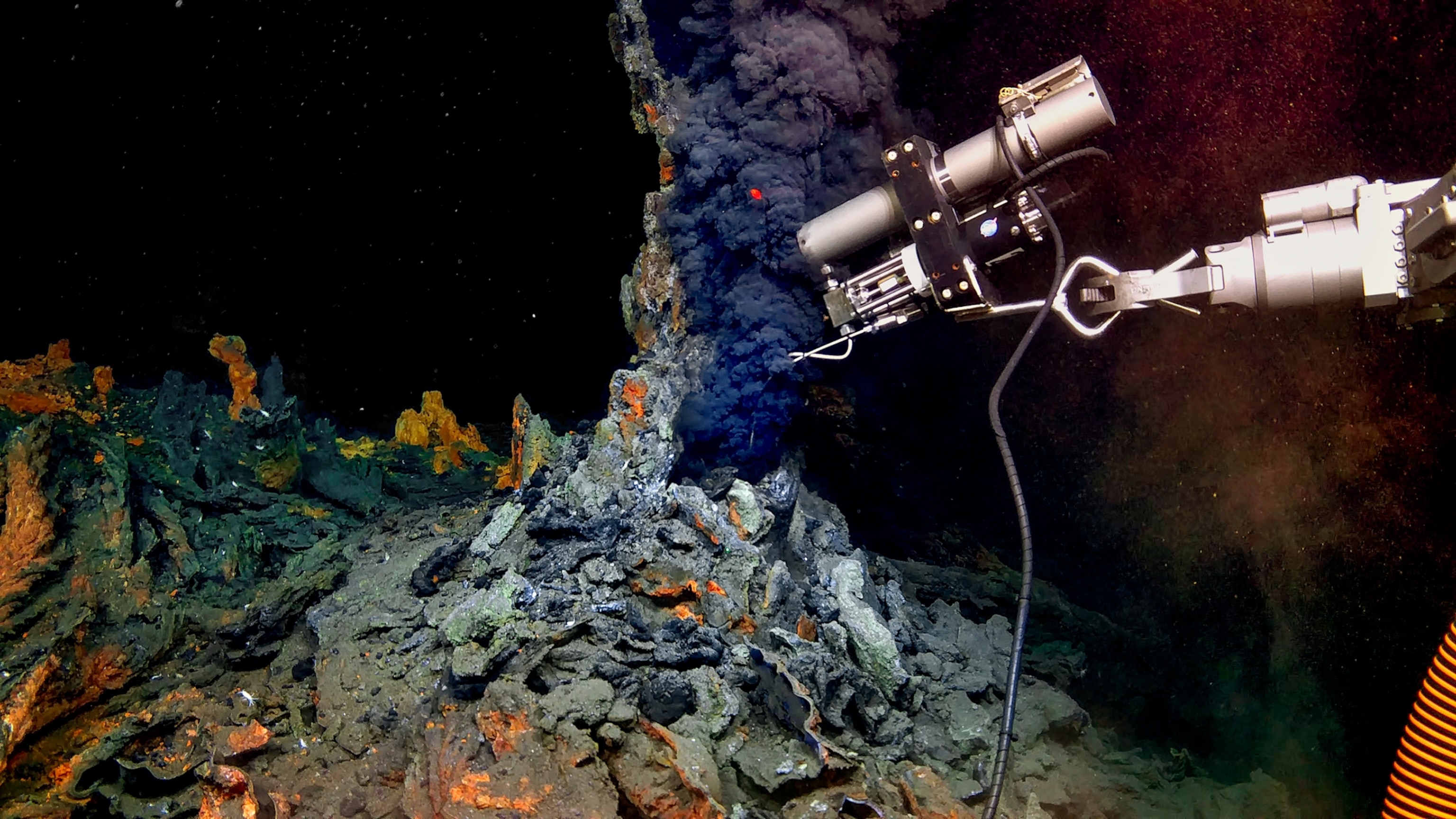 Isobaric gas-tight sampler in a hydrothermal black smoker from the chimney in dark blue and orange ocean bottom.