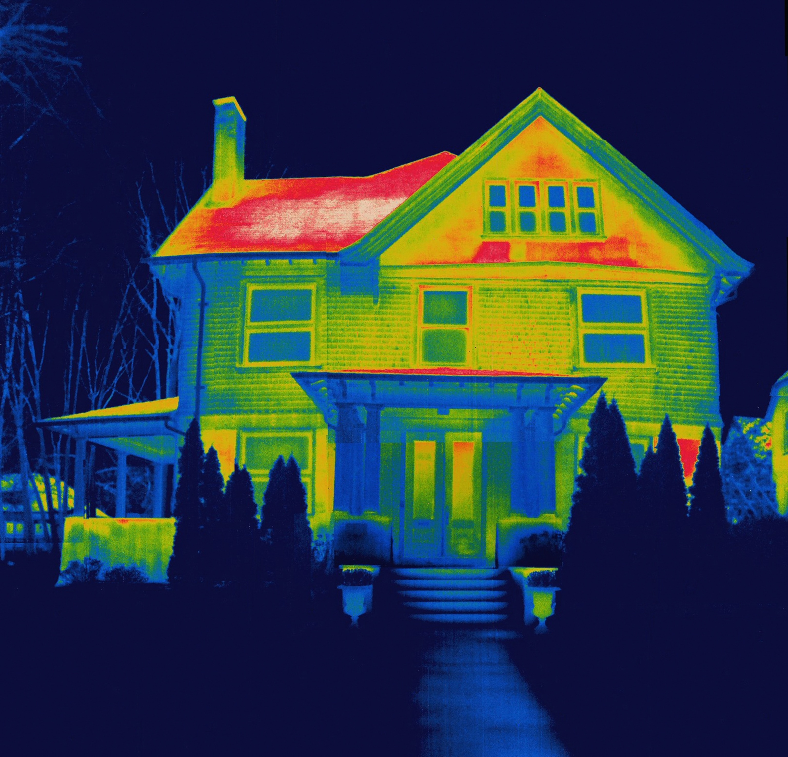 Thermal image of house; the roof is colored red and yellow, where most of the heat from the sun is collecting, while the rest of the house is shades of blue, green, and yellow.