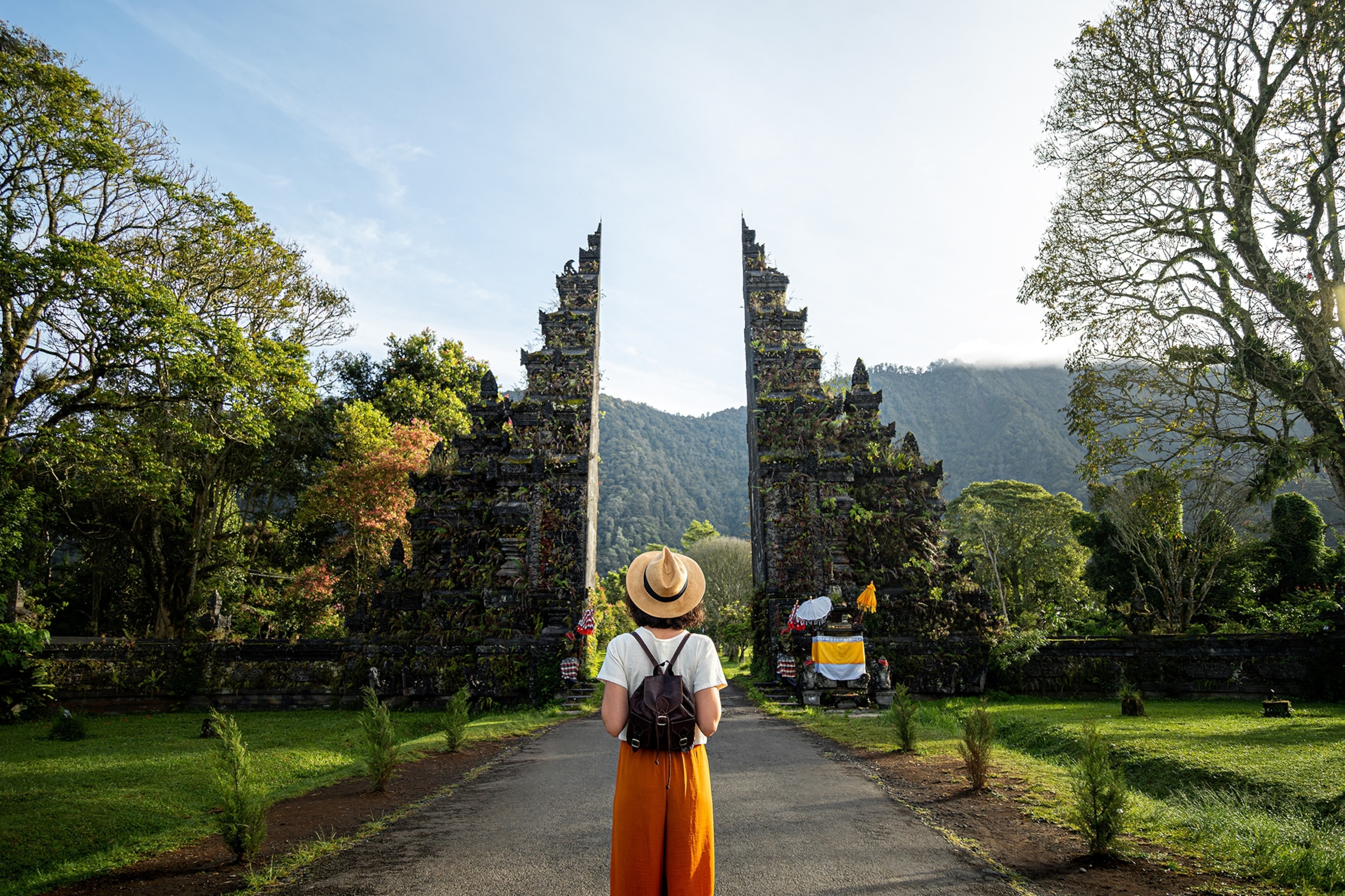 Woman tourist traveler with backpack enjoying walk through Balinese Hindu temple.