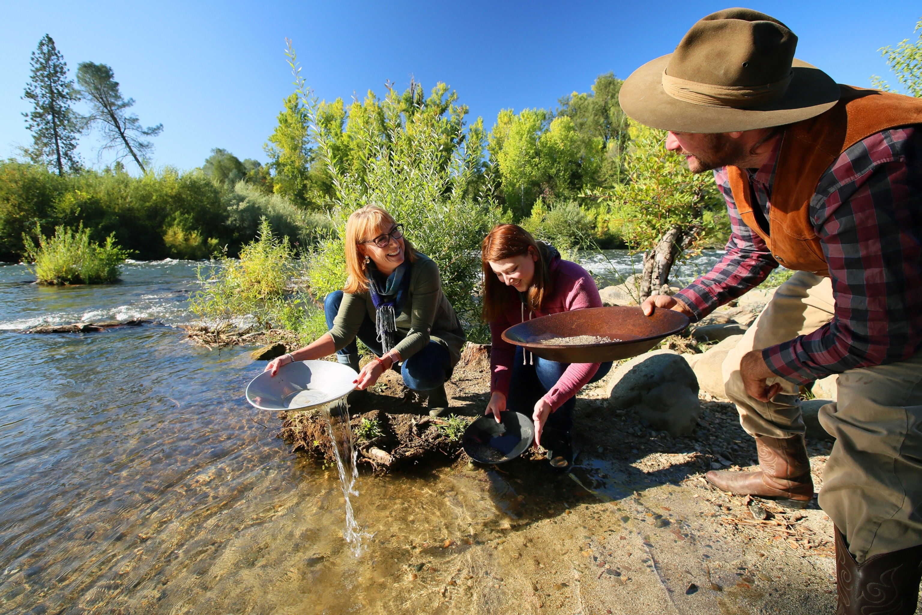 Tourists trying out panning for gold on the banks of the American River.