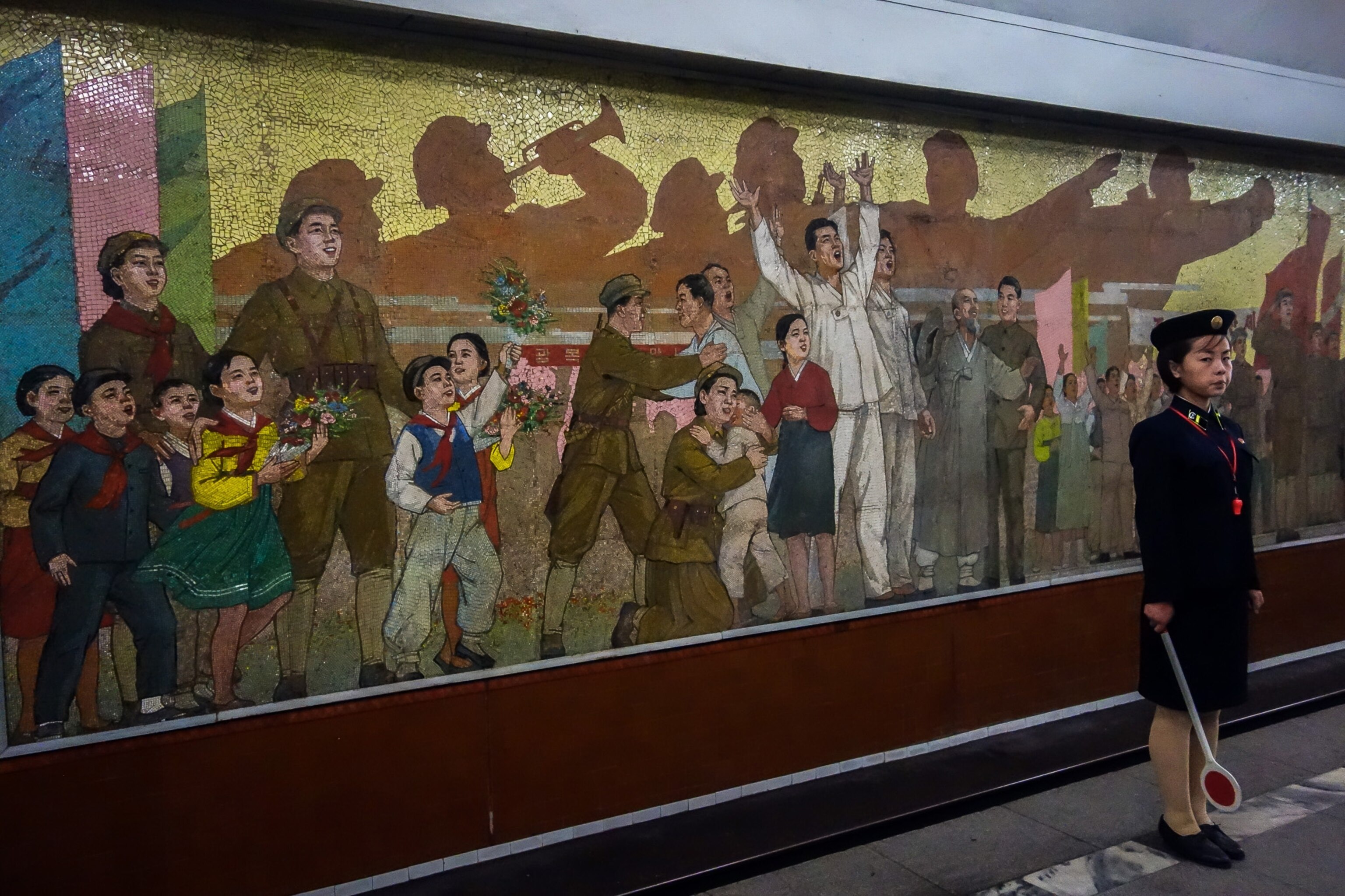 a train attendant in front of a mural