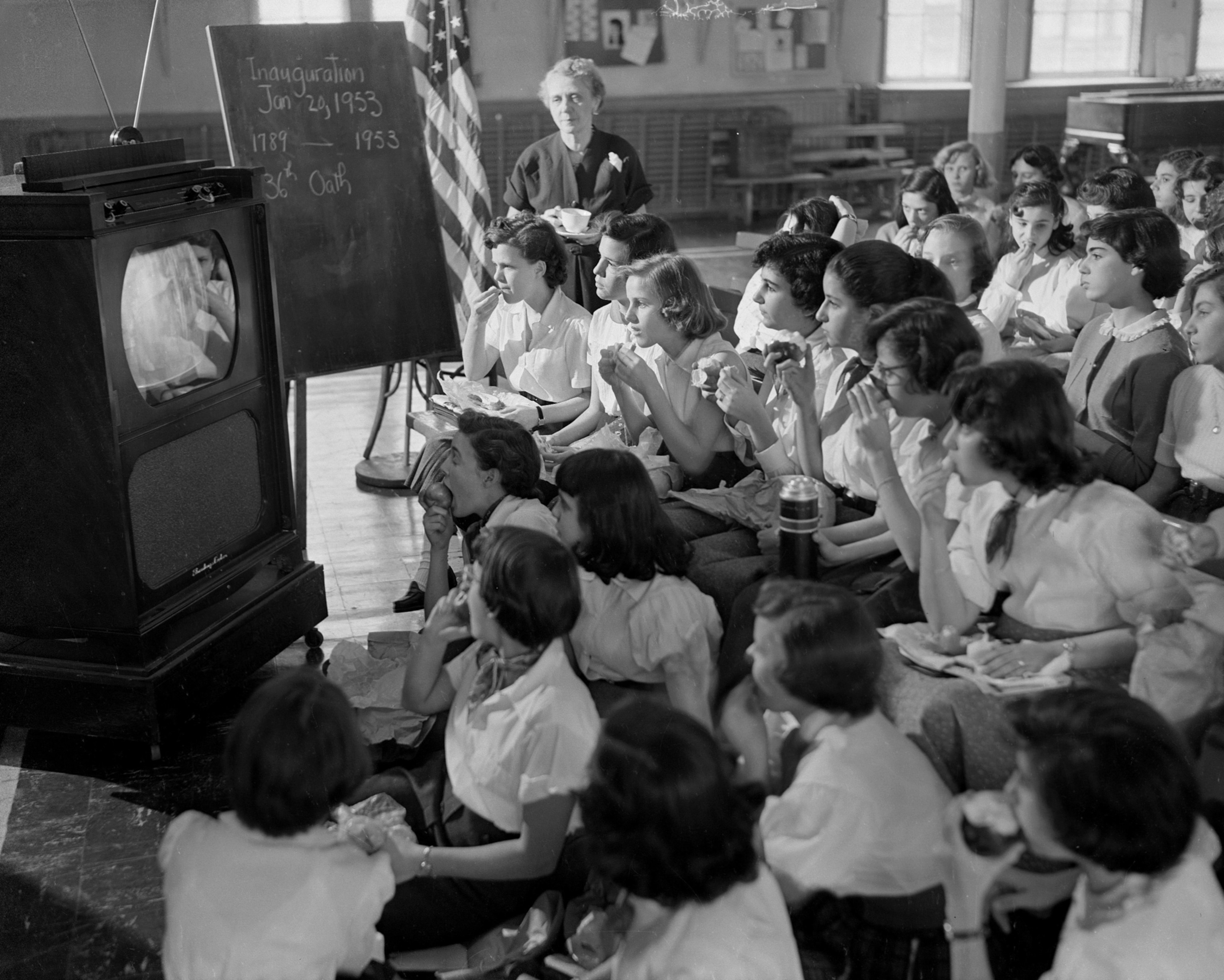 a group of school girls watching a television