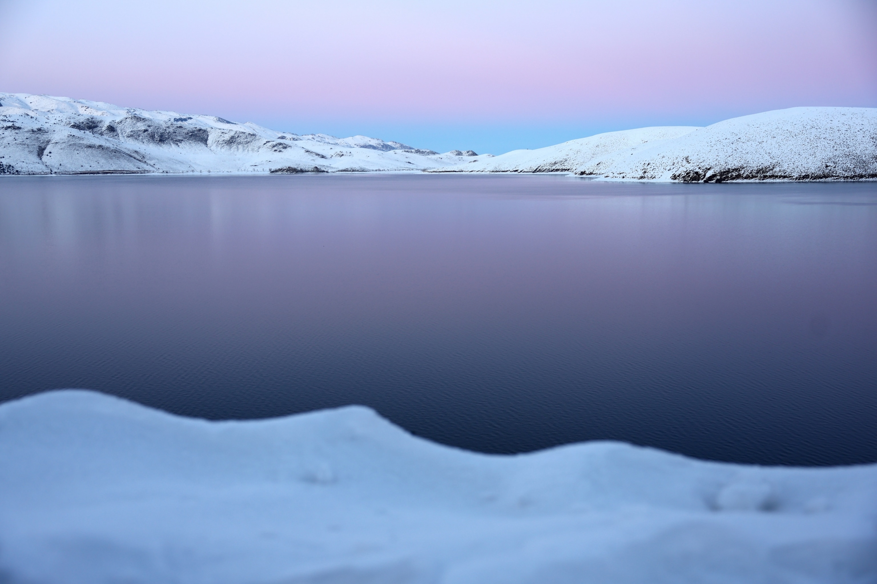 Still waters of Topaz Lake are seen beneath a purple and blue sky.