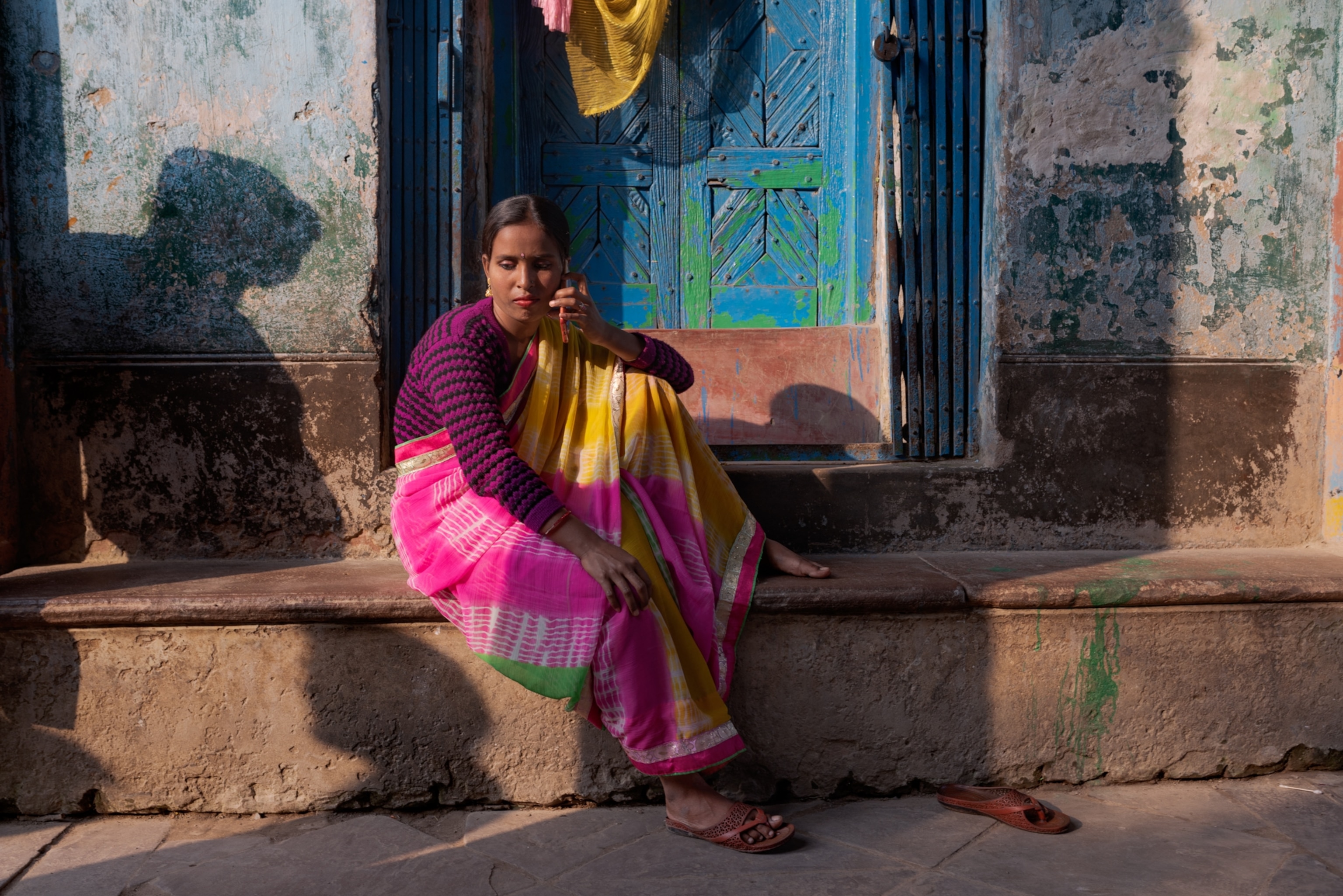 a woman sitting on a step outside of a building on the phone