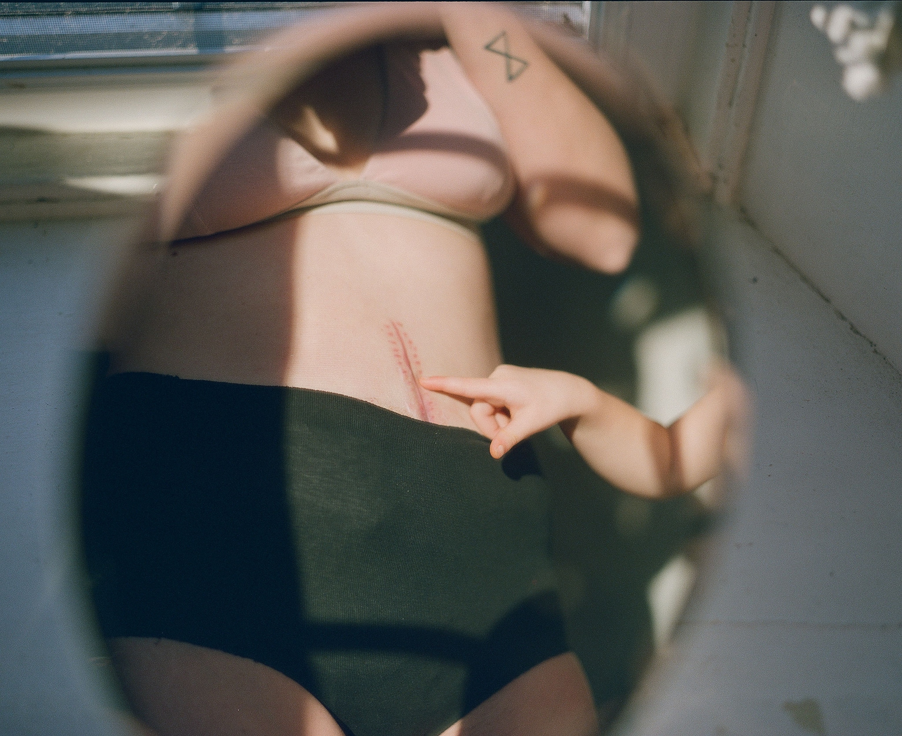 a woman with a scar on her stomach takes a photo in a mirror