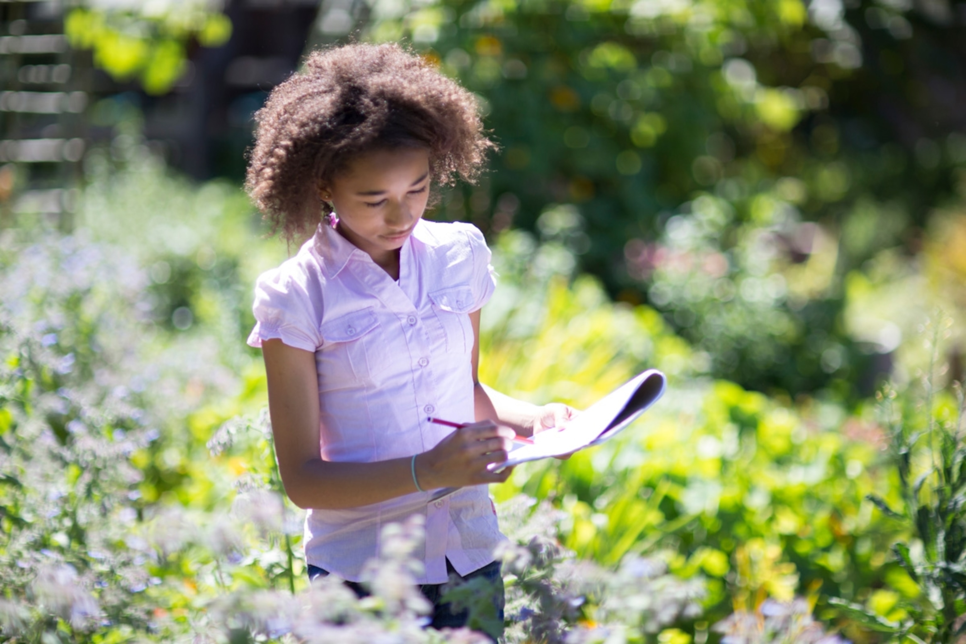 Girl (aged 13) drawing plants while on a school field trip in nature. Cape Town, South Africa
