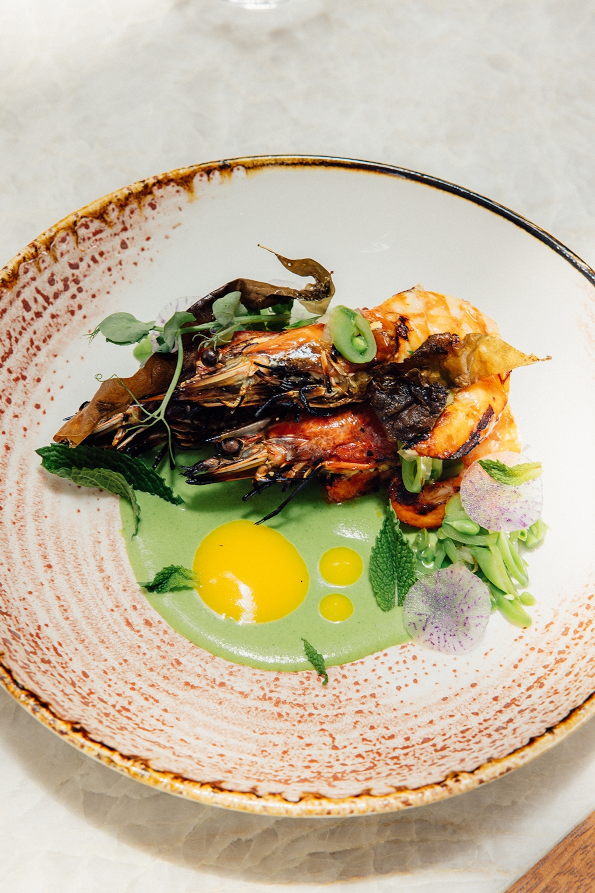 Shrimps served alongside a green sauce on a plate