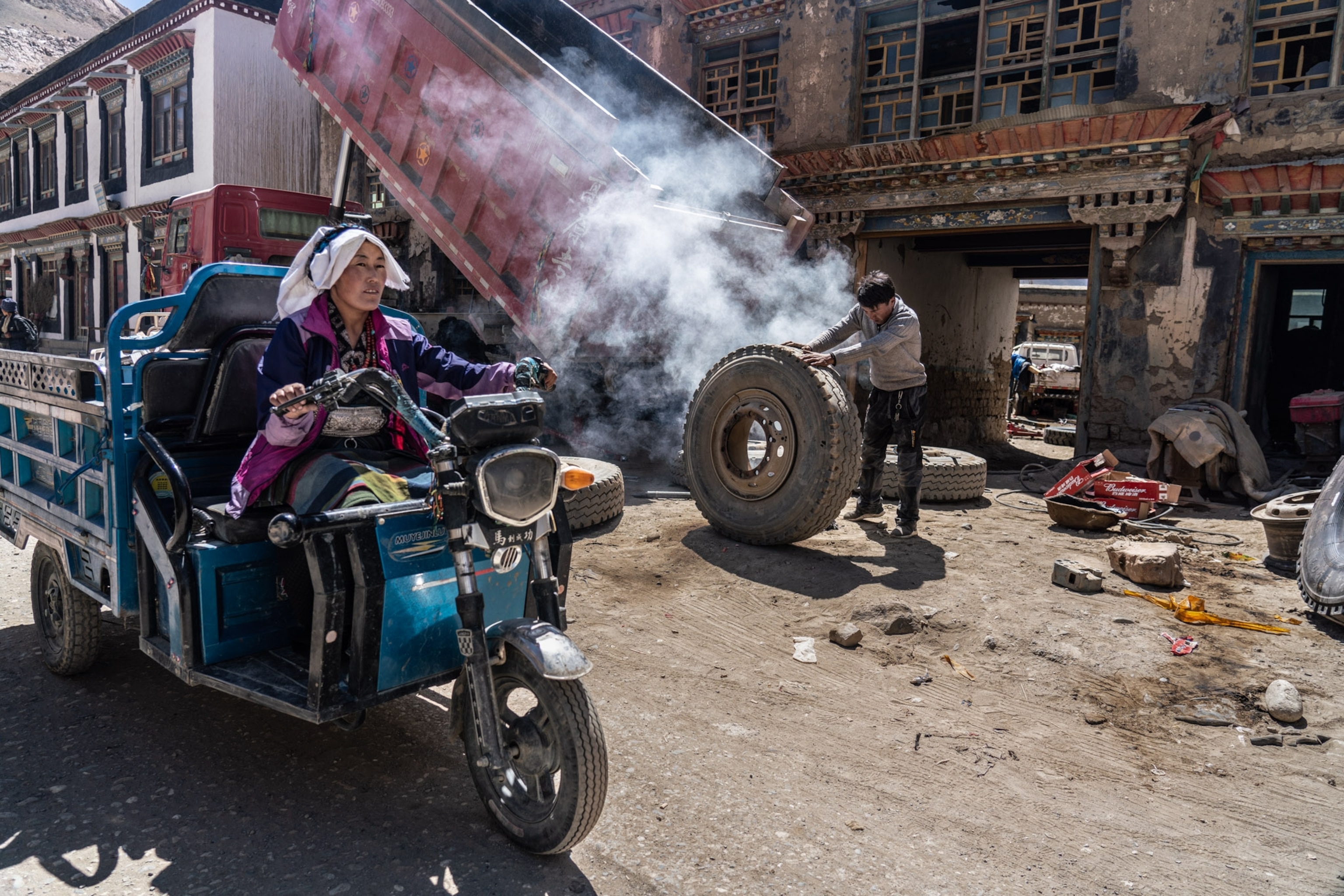 a woman on a two wheeled motorcycle-like vehicle driving through a town