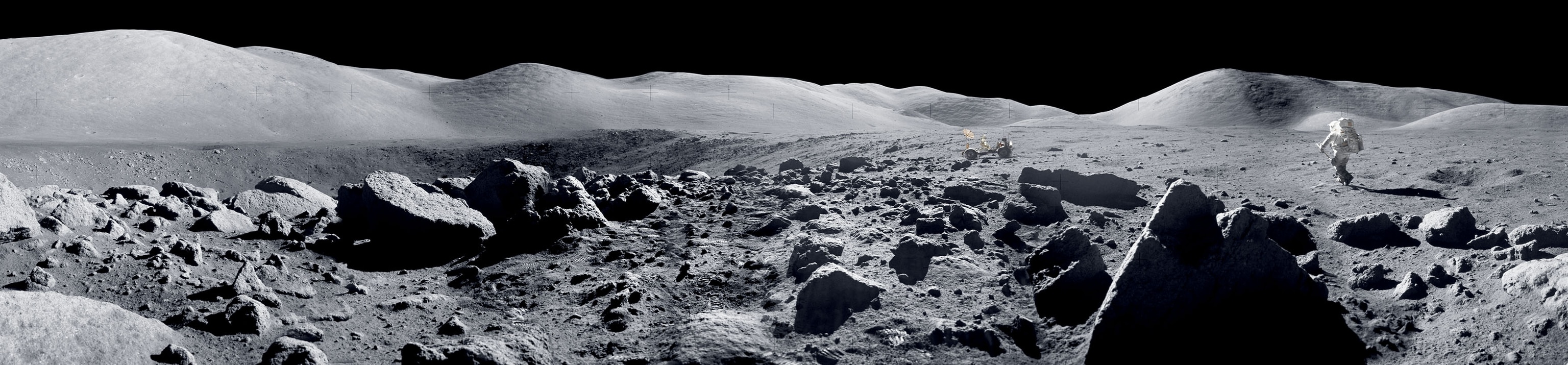 Panoramic image of an astronaut walking on the rocky lunar surface towards a rover