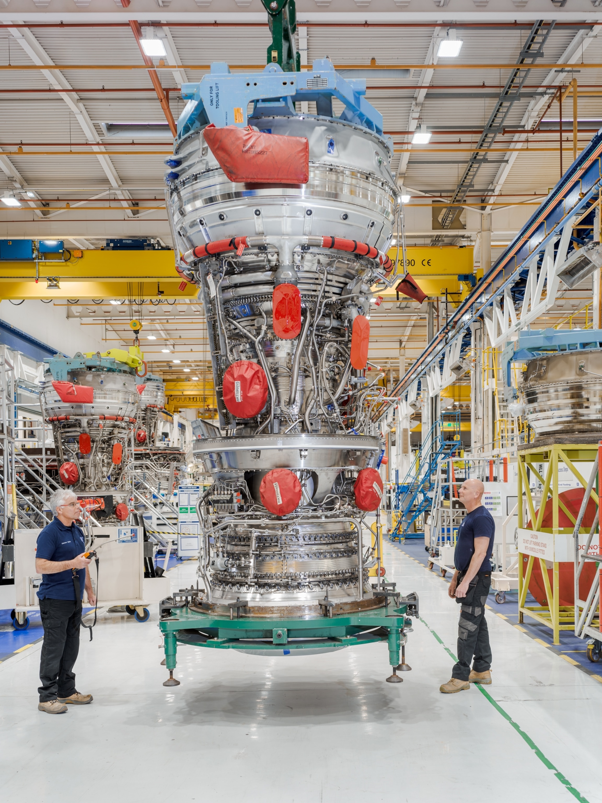 Picture of two persons standing next to complete turbofan engine.