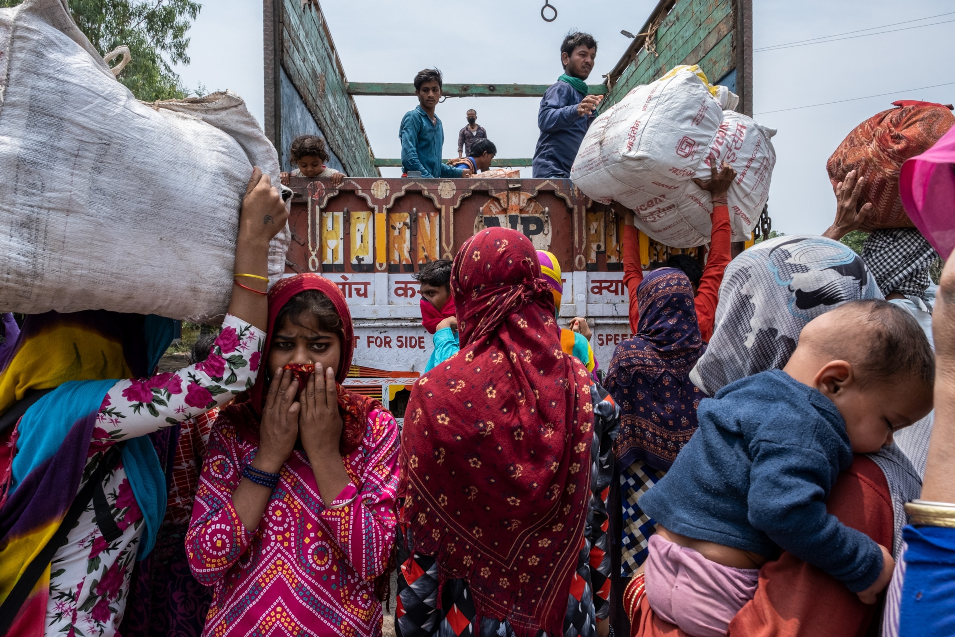 migrants climb onto the back of a truck in India