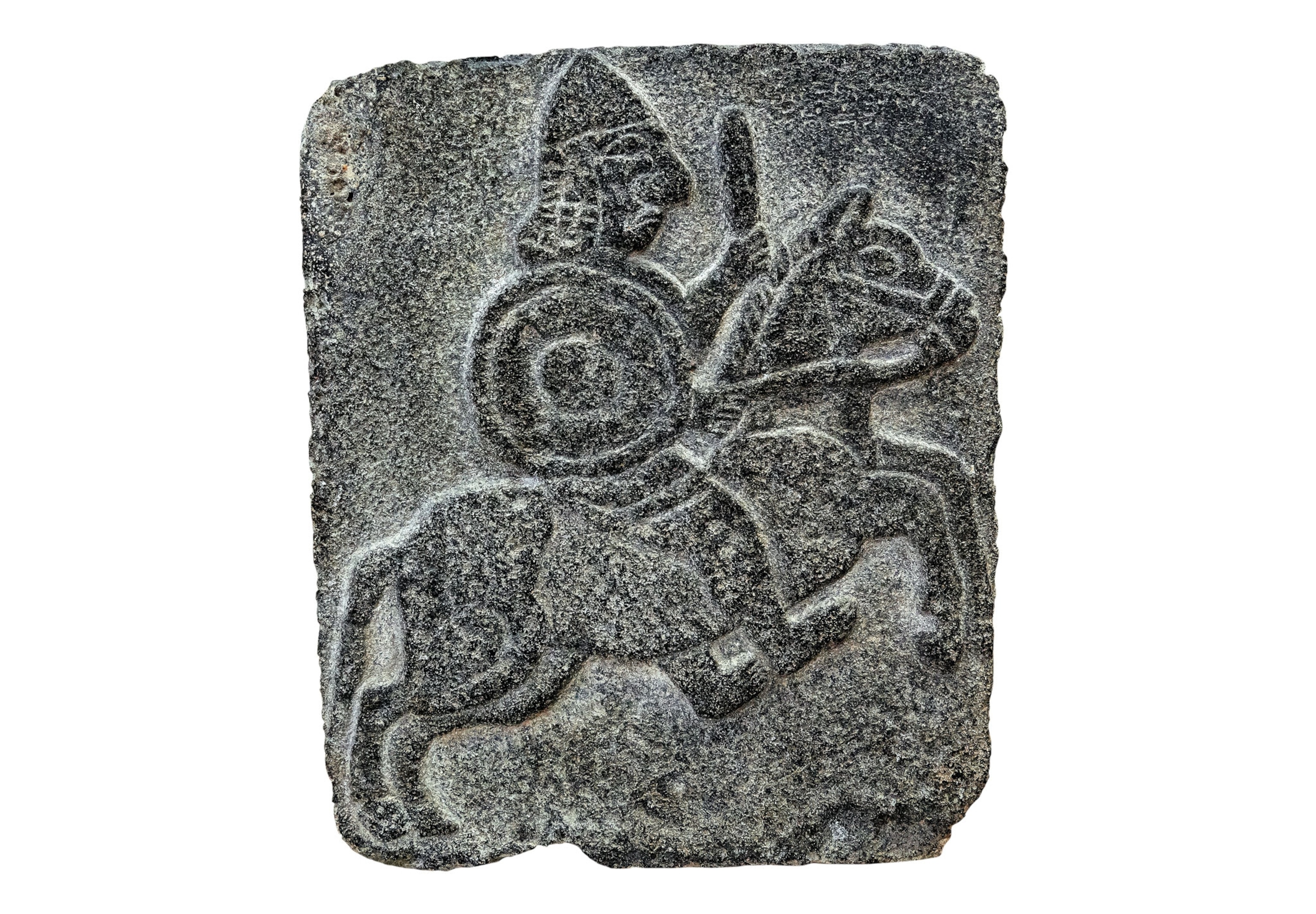 a stone relief of a man riding a horse with a sword and shield