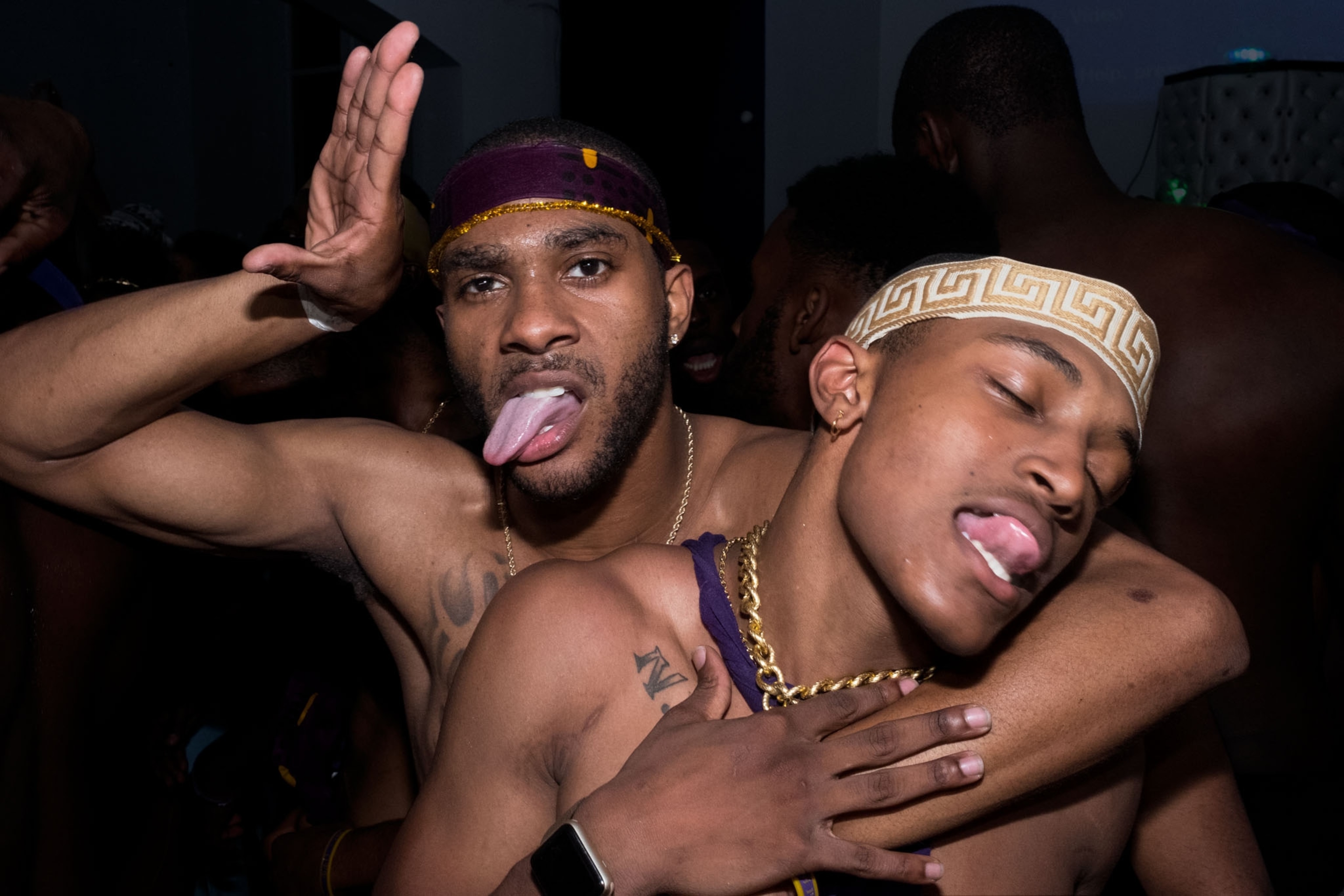 two young black men posing for a photo, sticking out their tong during a party