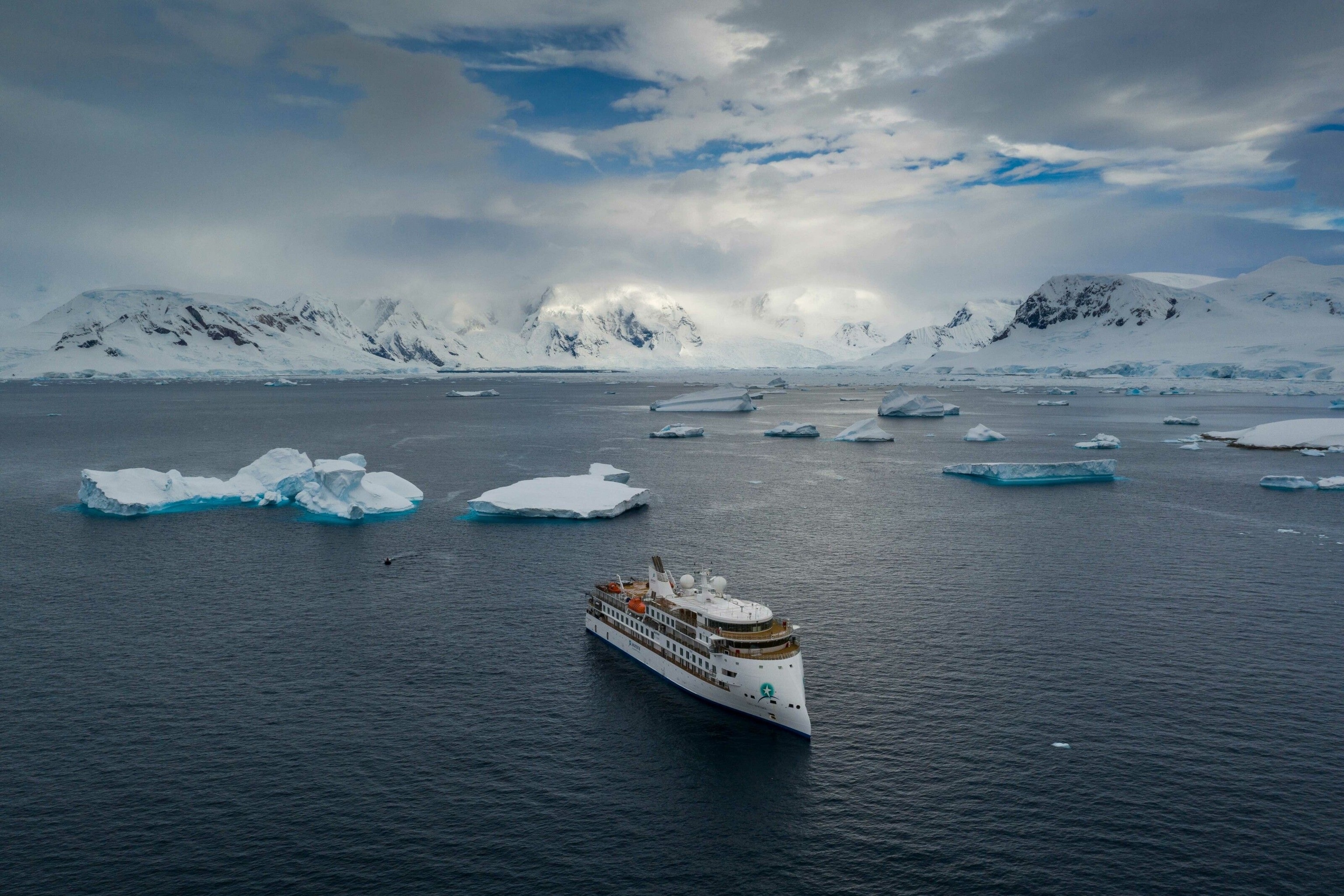 A cruise ship in Antarctica, gliding around small icebergs.