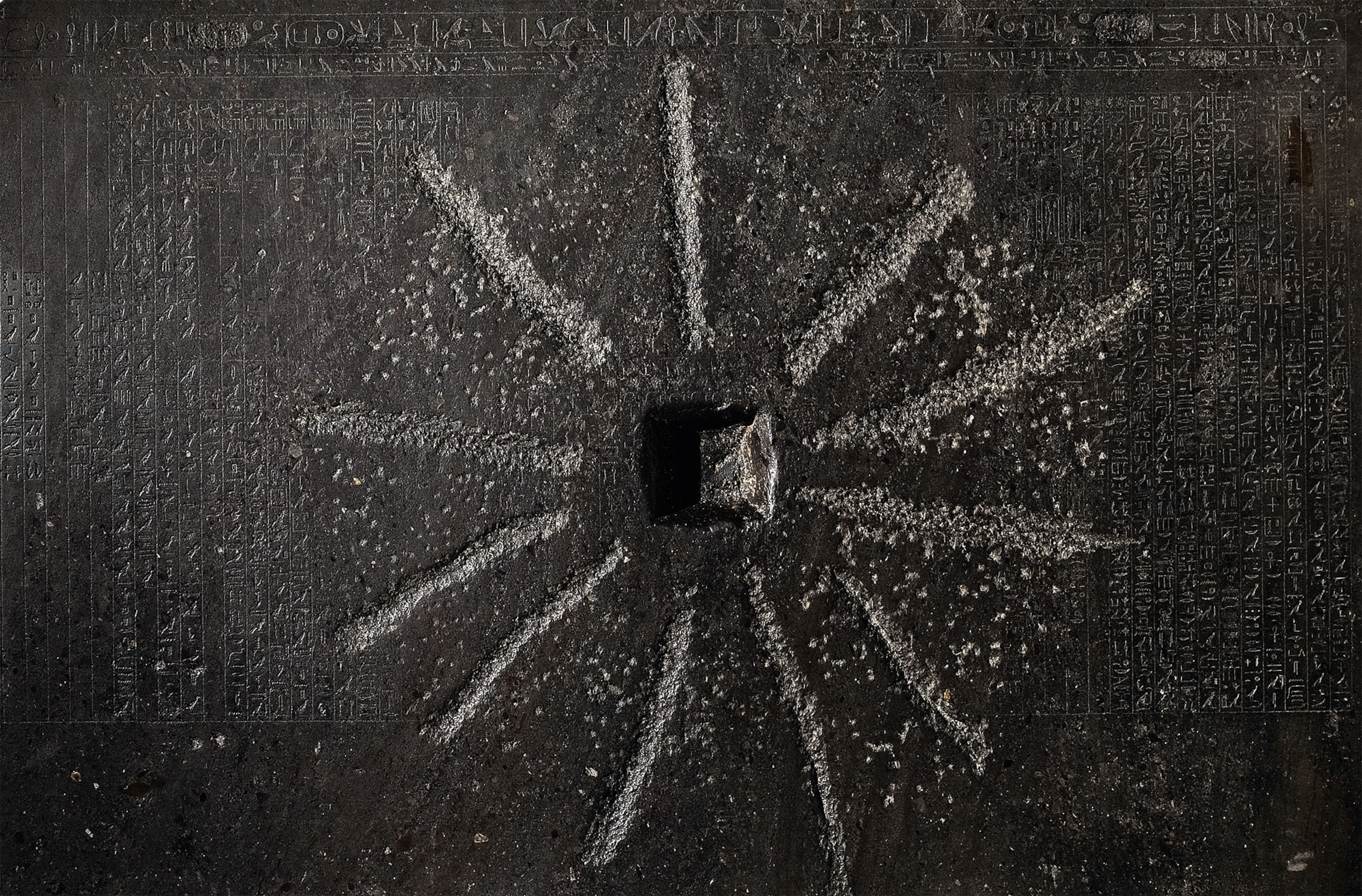 A dark stone with inscriptions and a star shape carved in it