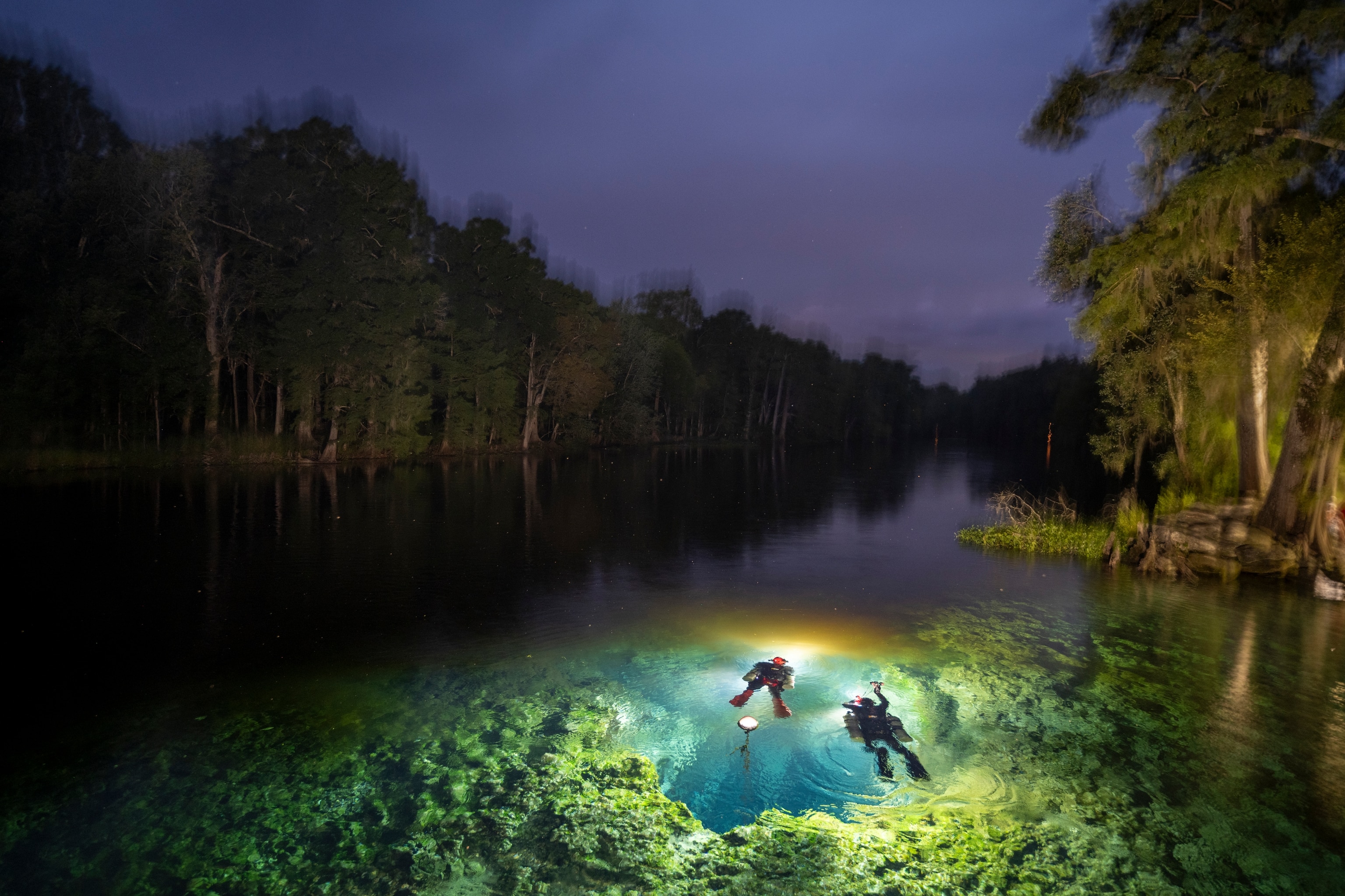 A pair of cave divers prepare to enter the Devil's Ear, a limestone rift in the bottom of Florida's Santa Fe River gushing with crystal clear groundwater from an underlying aquifer. The Devil's Ear is one of Florida's 33 first magnitude springs, the largest category of springs that discharge at least 64 million gallons of water per day. A controversial water bottling facility captures about 1 million gallons of water from the Devil's Ear and nearby springs before it reaches the Santa Fe River every day.