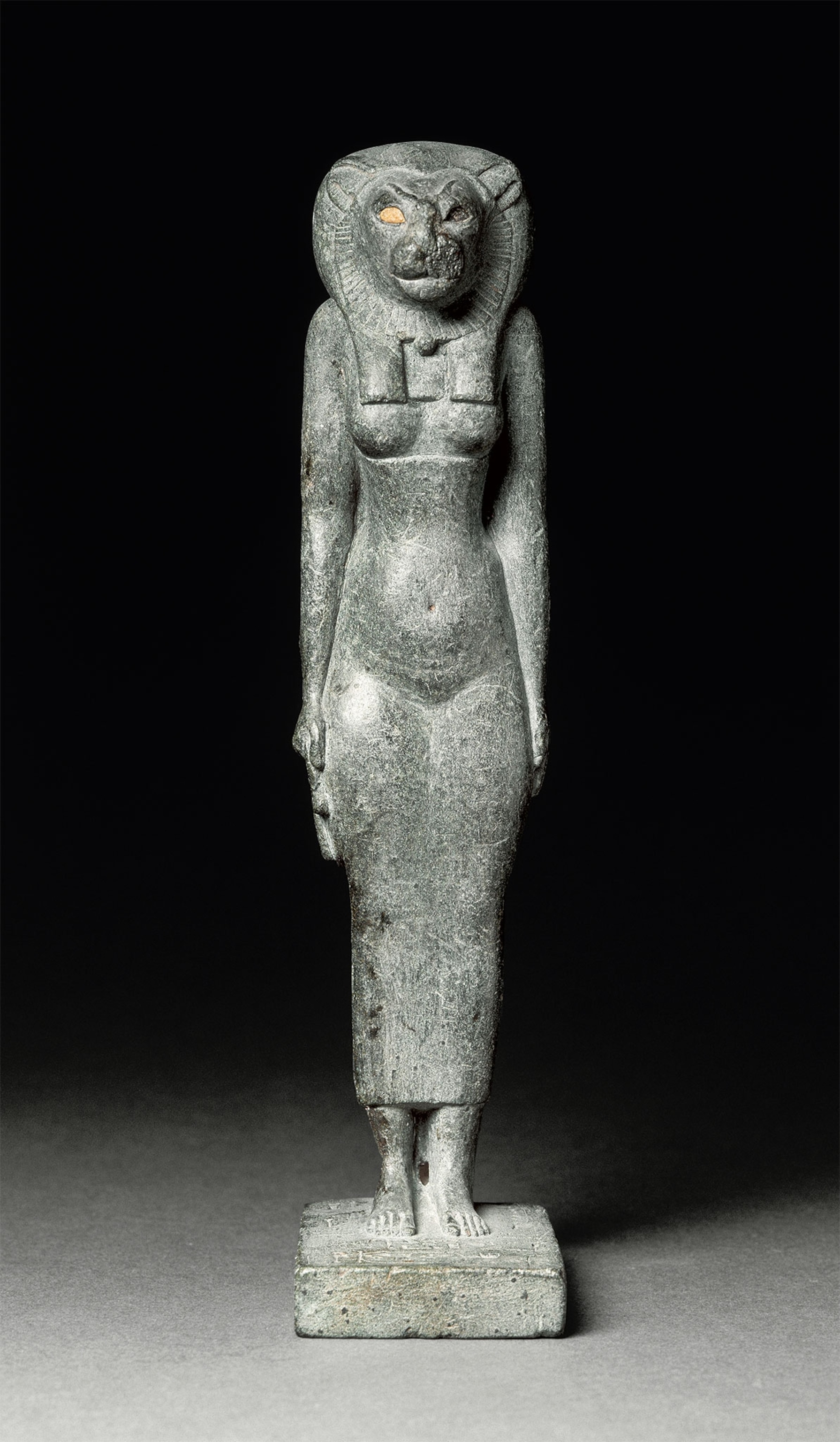 A stone statuette of a goddess with a feline head