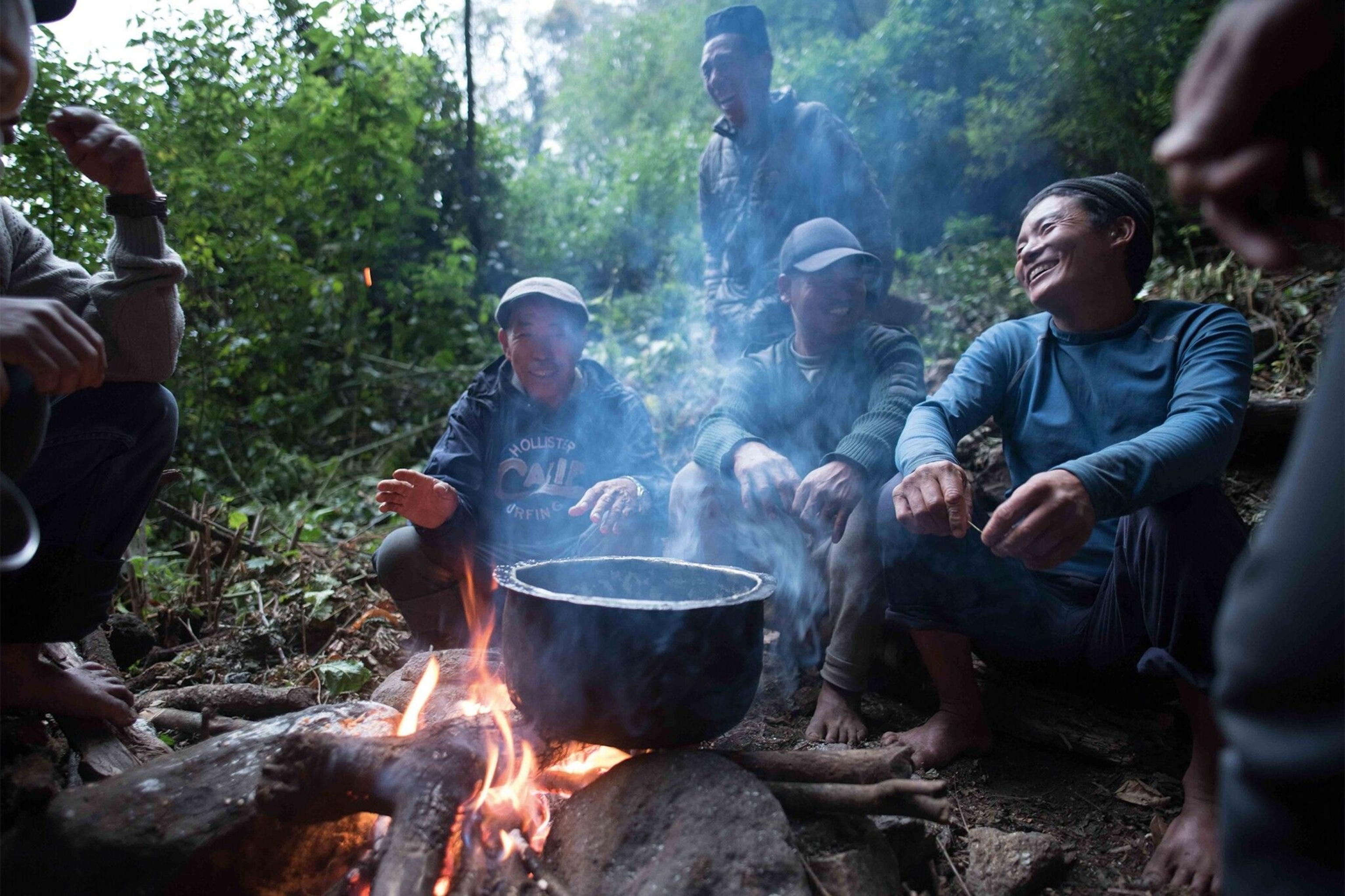 Honey hunting members of the group sitting around a camp fire