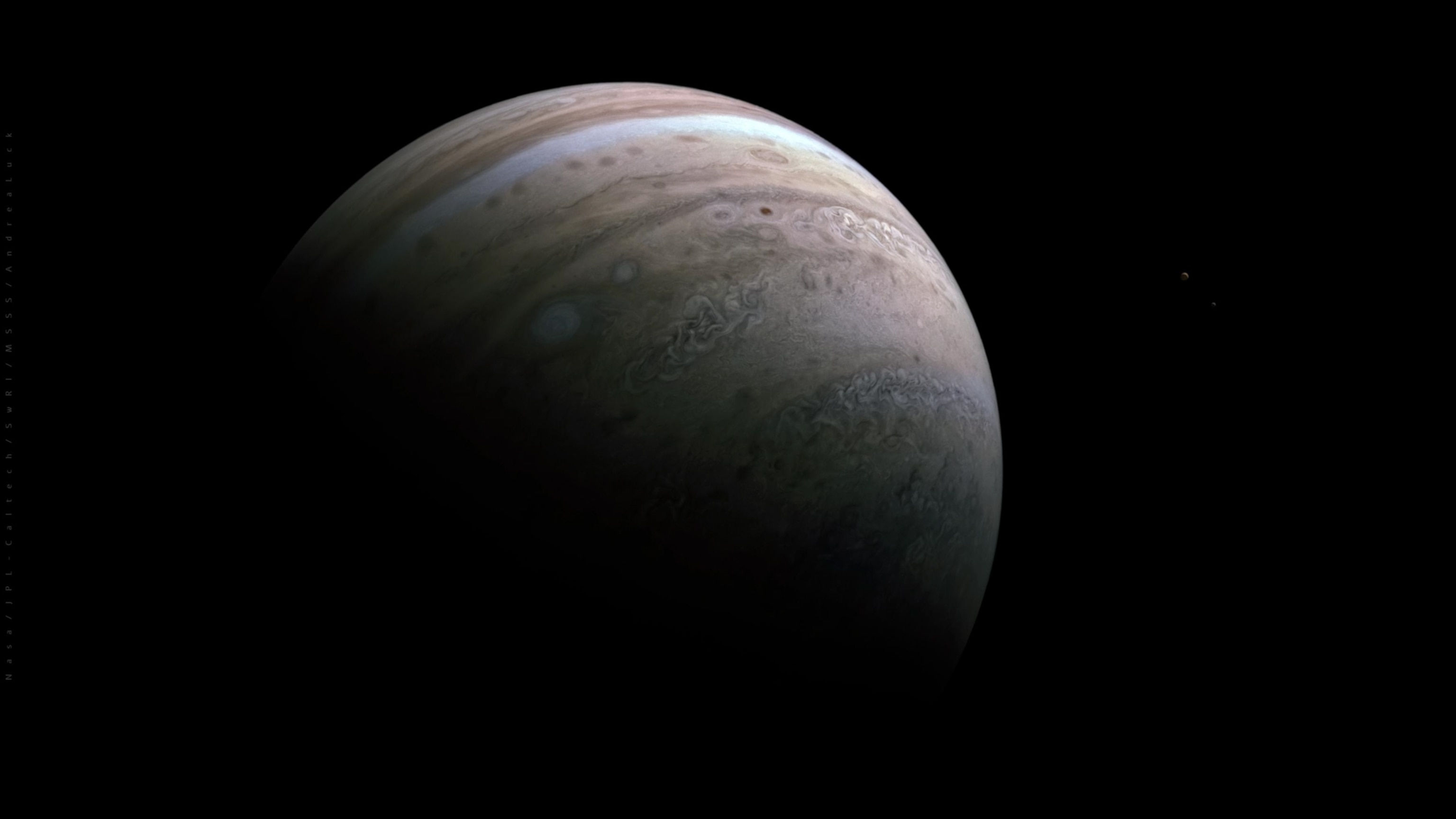 Two small moons dwarfed by the enormous size of Jupiter
