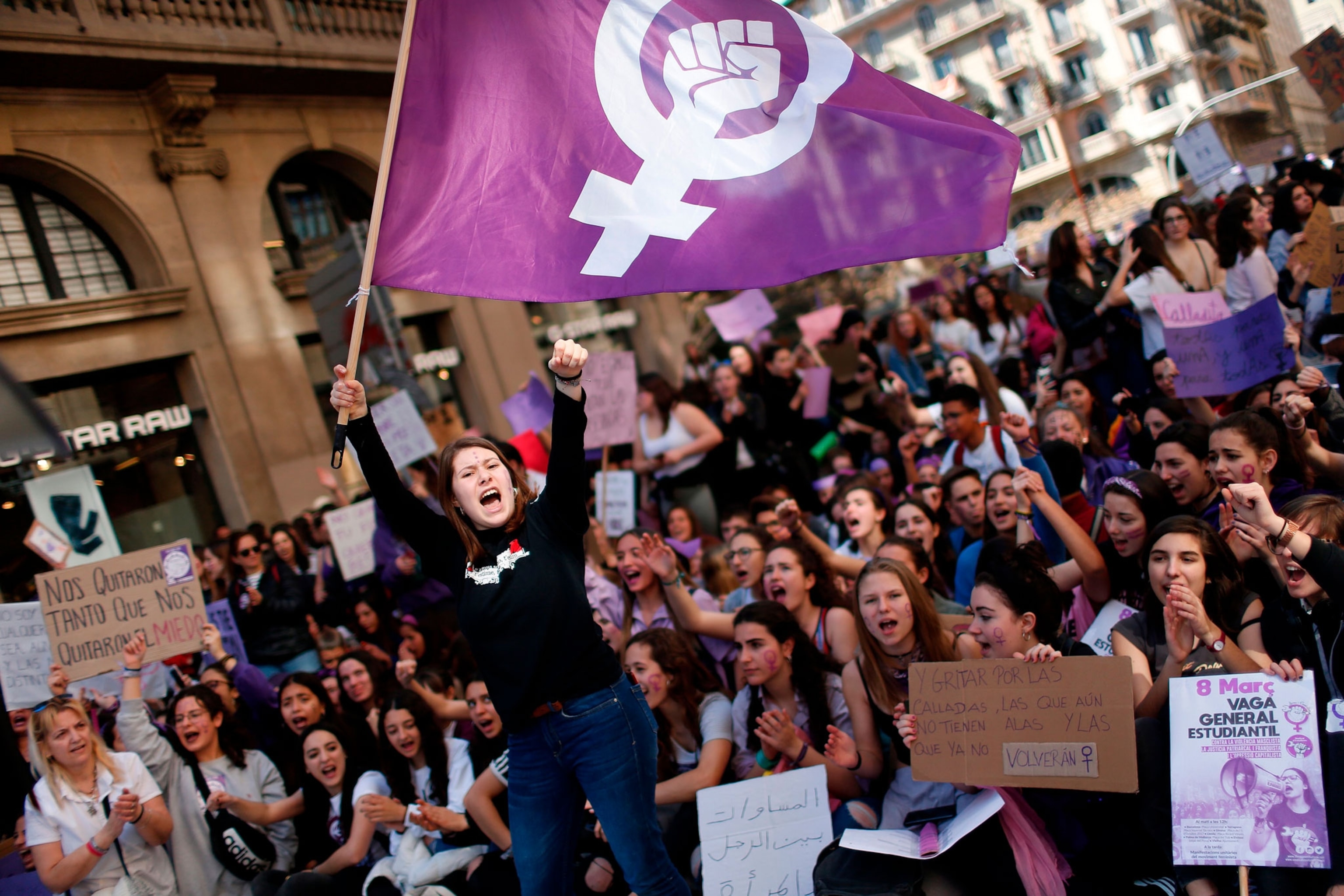 a woman waving a feminist flag at a demonstration while raising her fist