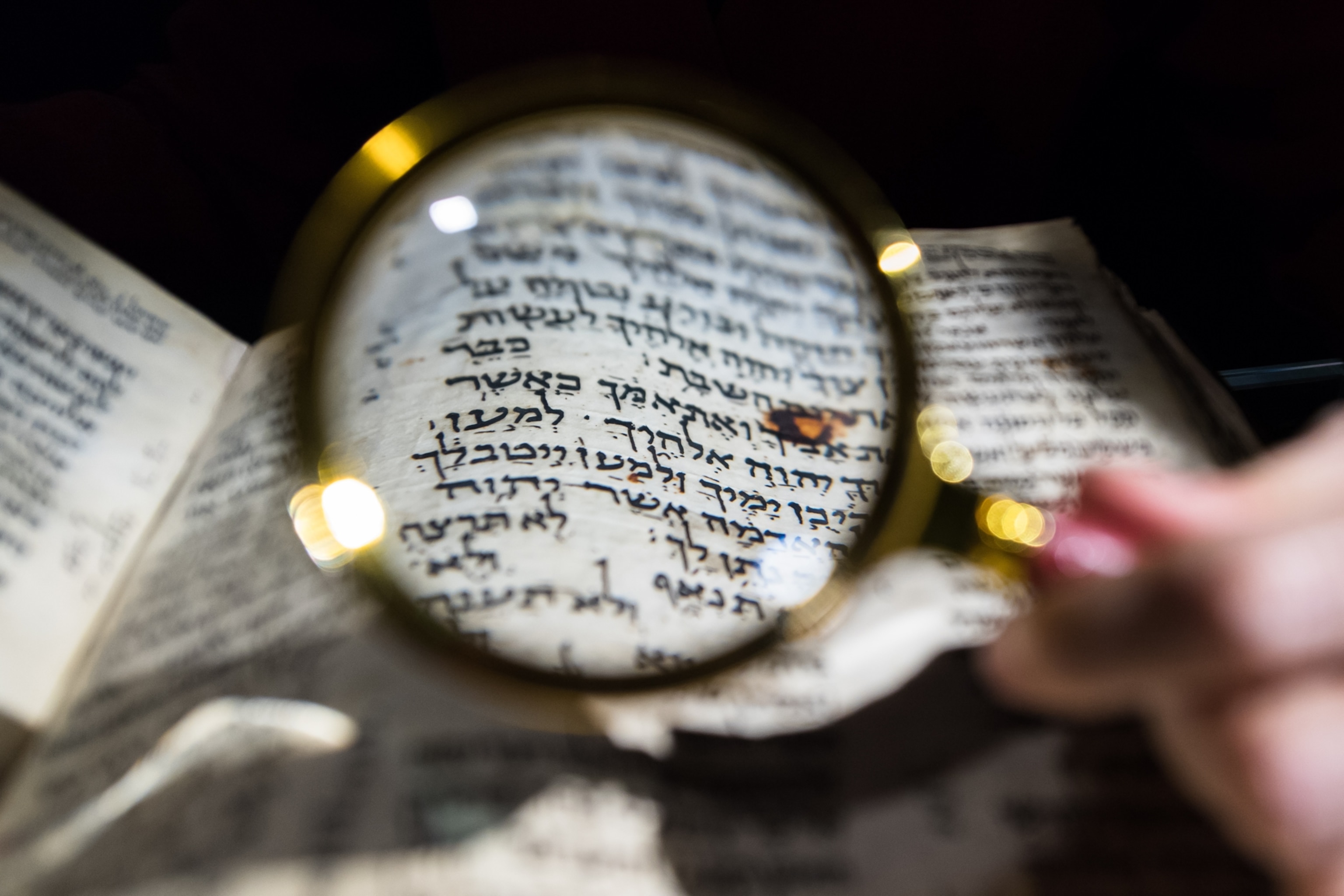 A section of the Ten Commandments, written in Hebrew, is seen under a magnifying glass