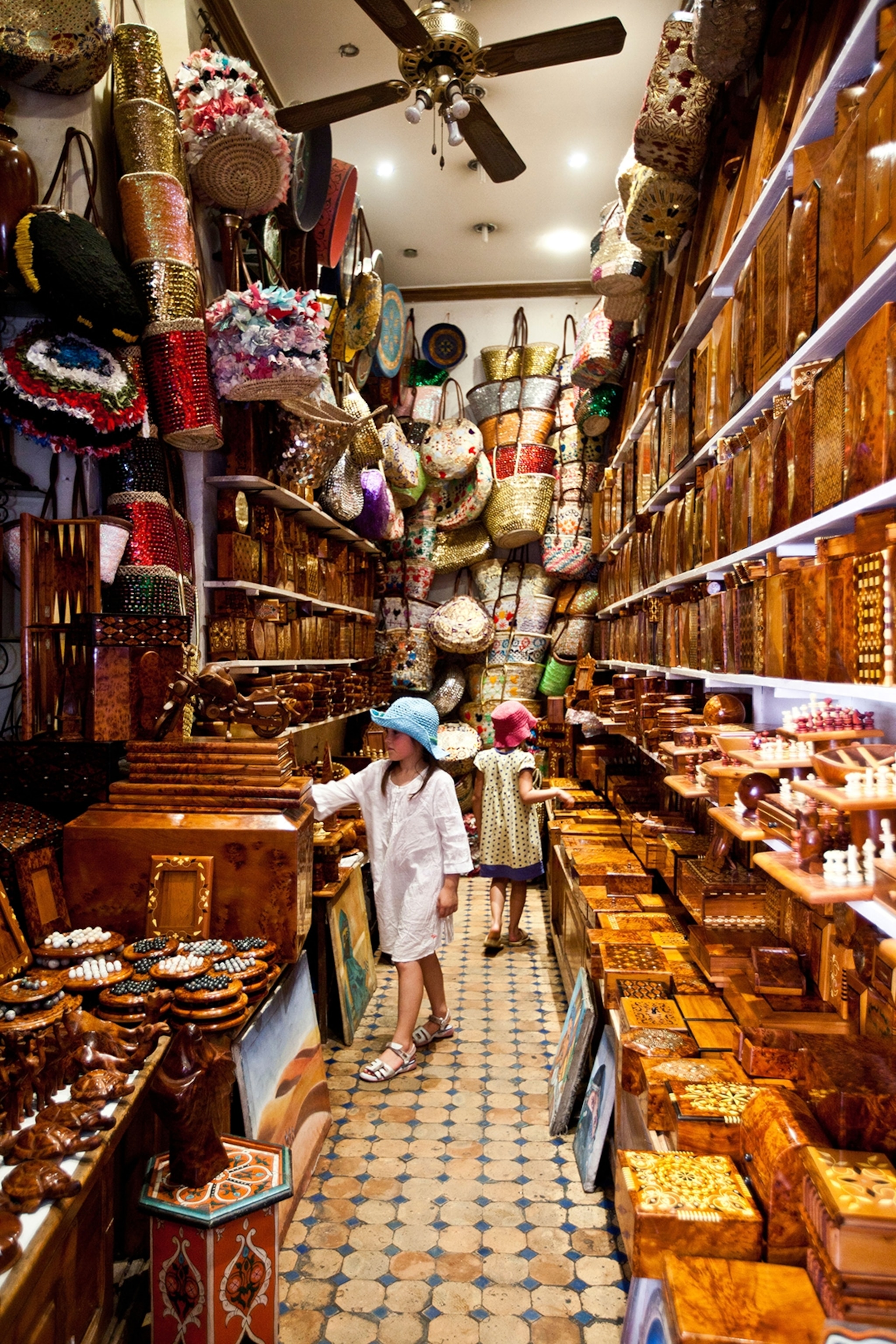 Children browse in a store in Marrakech's medina with local products stacked on the surrounding shelves.