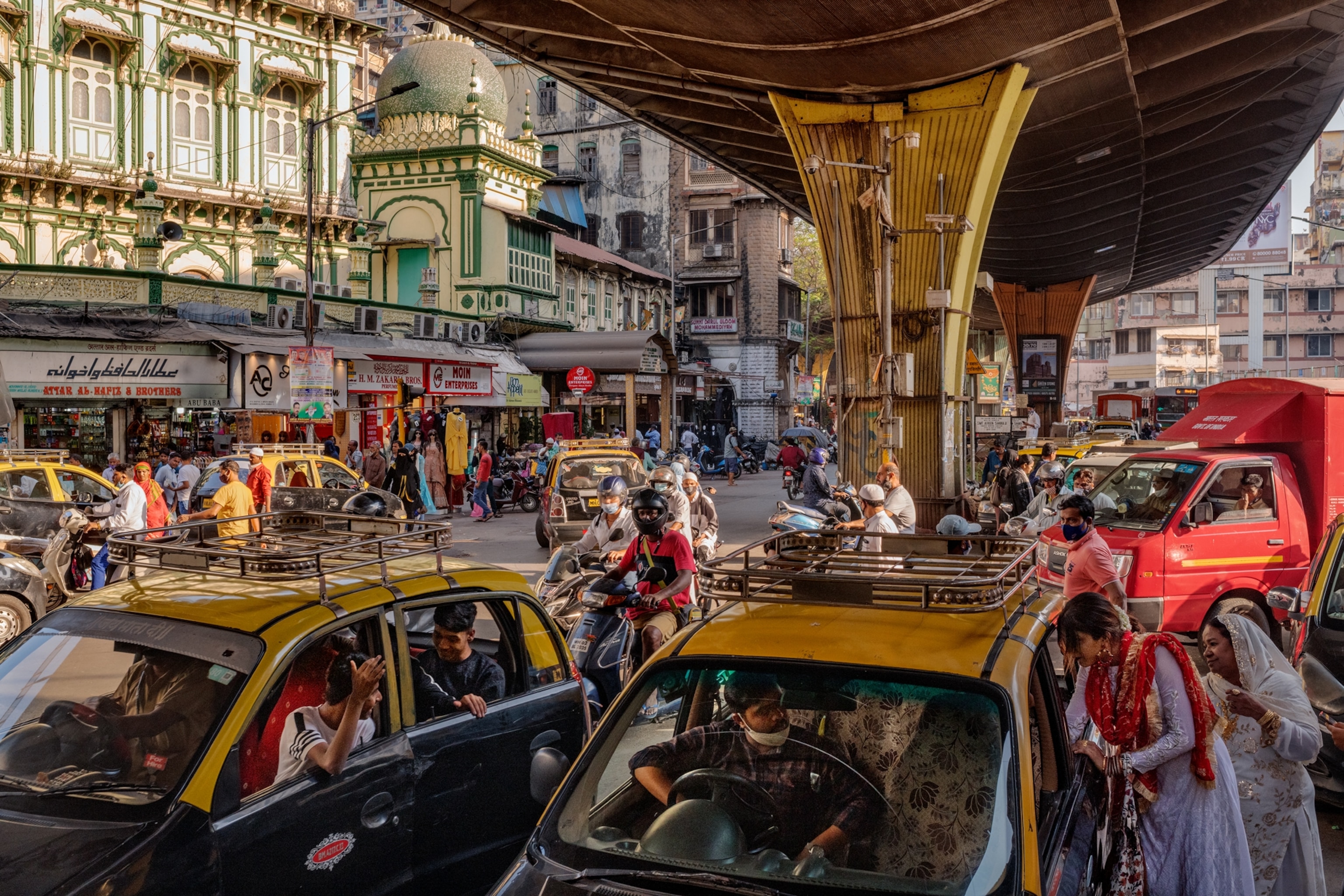 Picture of Taxis and pedestrians under bridge.