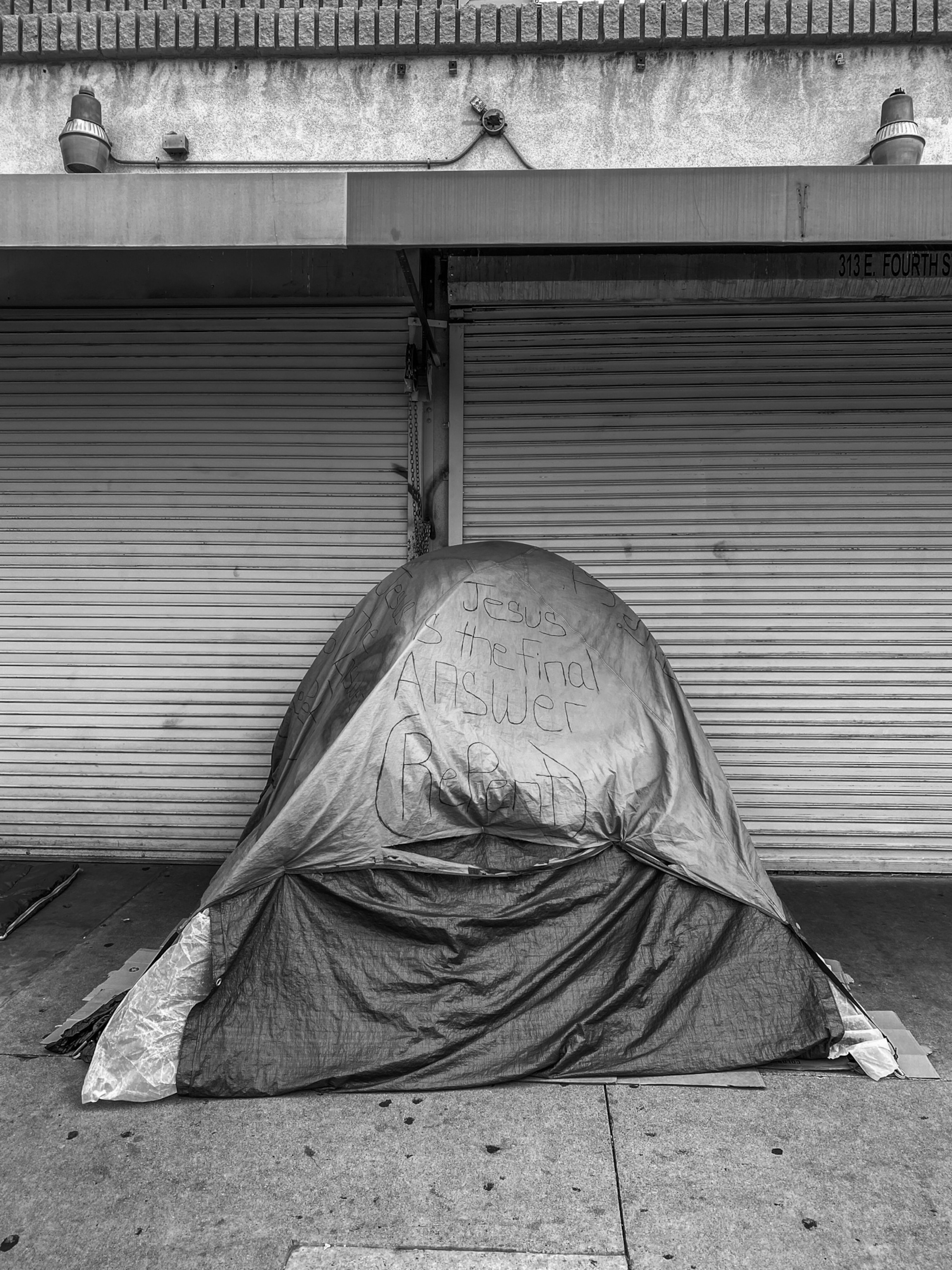 a tent on a sidewalk with the writing "Jesus is the final answer"