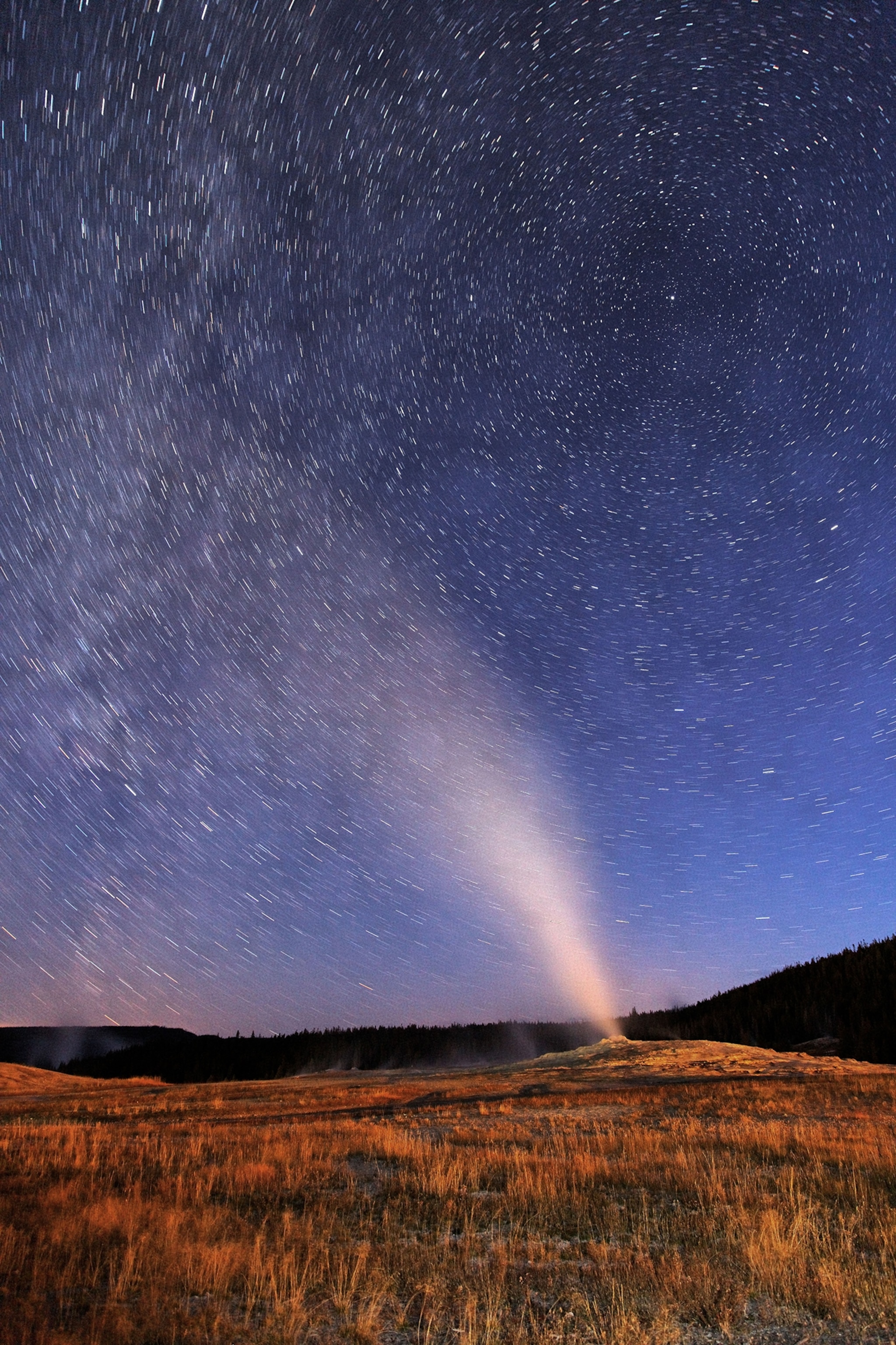 Old Faithful Geyser in Yellowstone National Park erupting at night